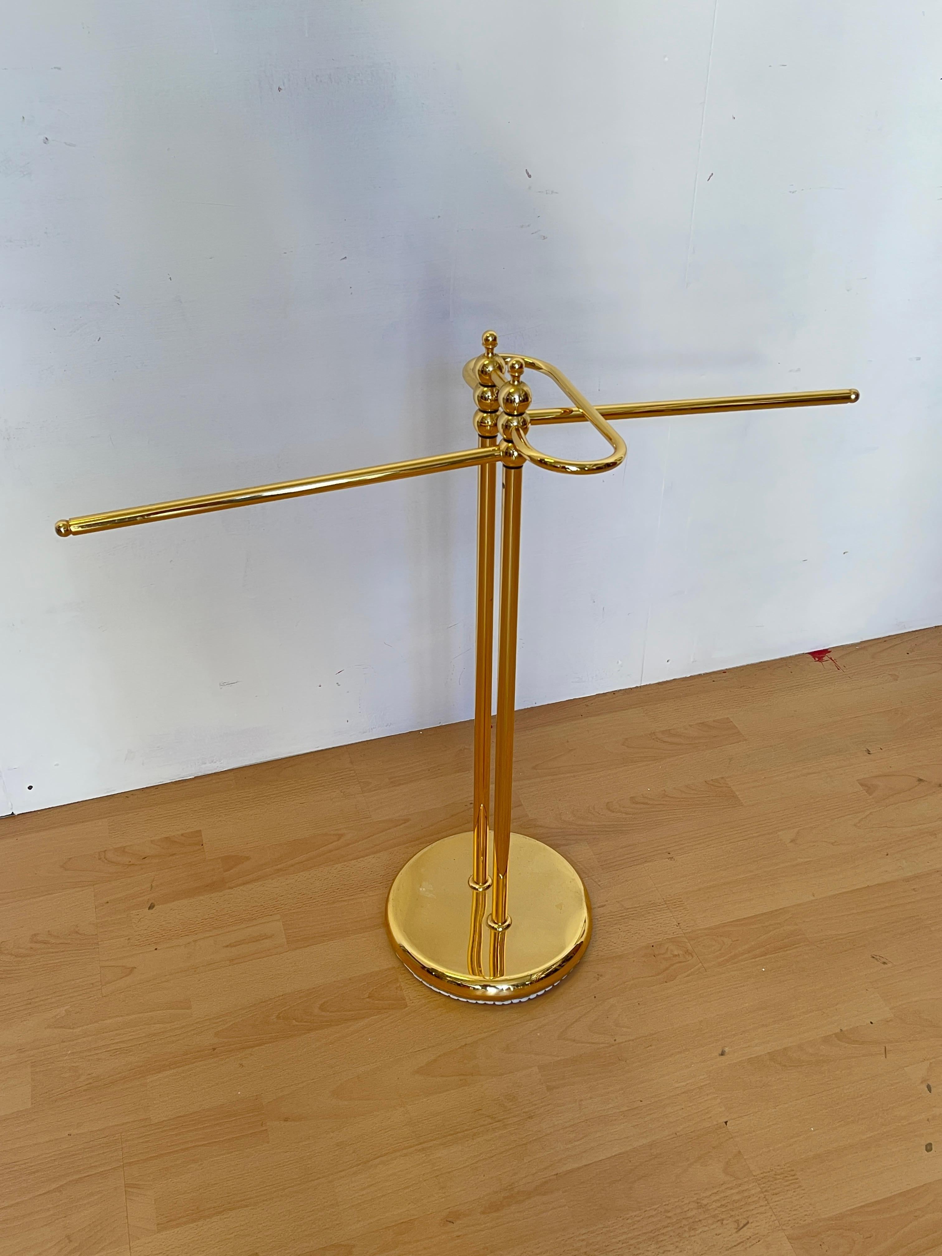 Raffinato portasciugamani da terra in metallo con finitura dorata lucida, dal design elegante e senza tempo. Dotato di due bracci mobili e di una base stabile e pesante, è perfetto per aggiungere un tocco di classe al bagno o alla camera da