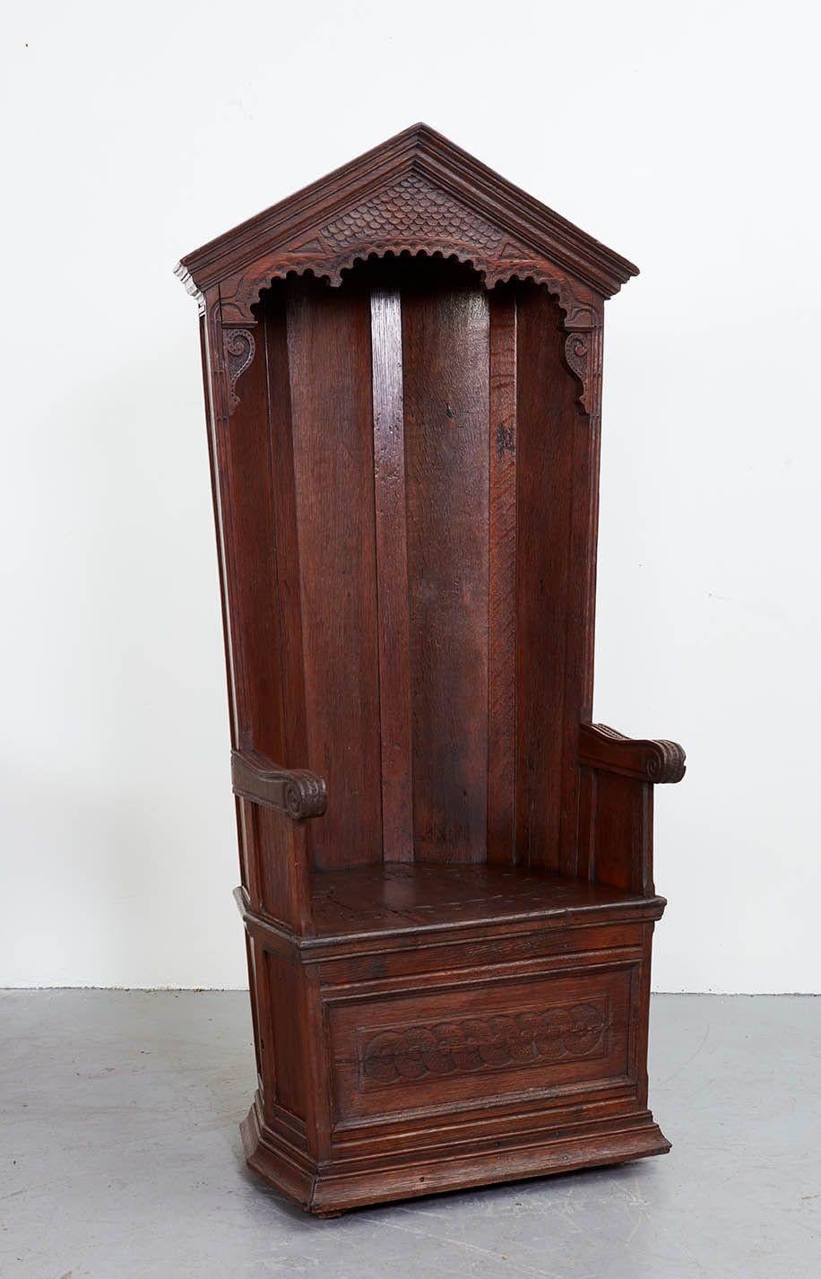A magnificant 19th century oak porter's chair with a five point shaped hood above a carved arch, surrounding a seat and arms, the back equally made for show and finished with architecturally formed side panels over a lower dado rail, matching panels