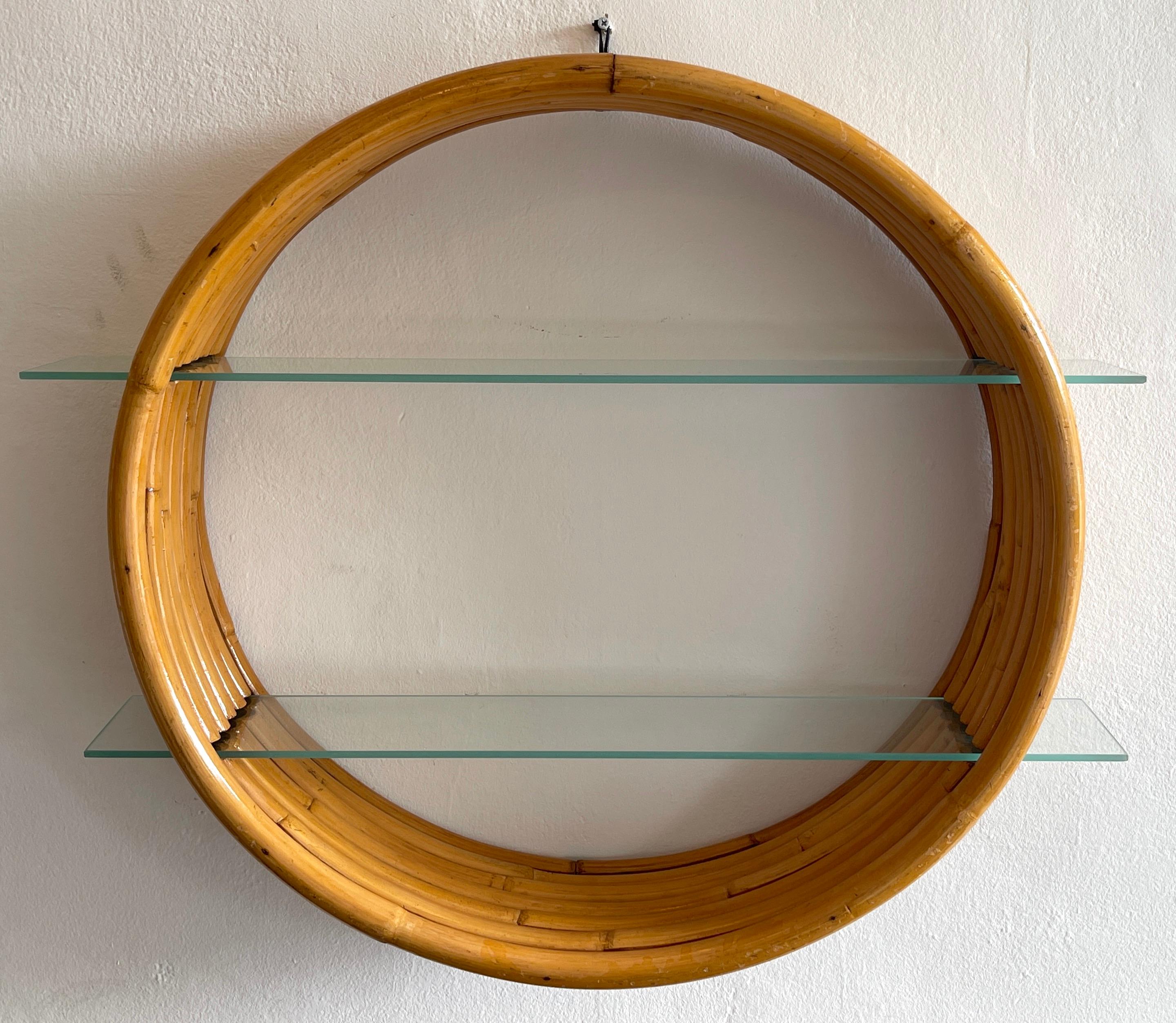 Porthole bamboo wall shelf, by Paul Frankl 
The circular frame with seven strands of thick bamboo, fitted with two interchangeable glass shelves
Measures: 30