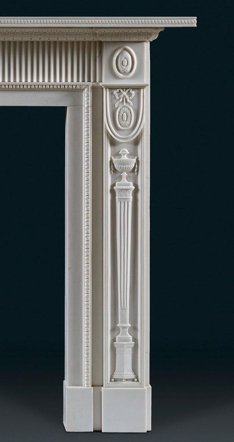 This elegant and refined neoclassical chimneypiece is in the 1790’s taste, with impressive Etruscan style jambs. Delicately carved urns sit on slender elongated pedestals below paterae held by ribbons, which are repeated on the frieze end blocks.