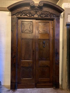 Portoncino doppio in noce con pannelli intagliati, completo di portale, italia