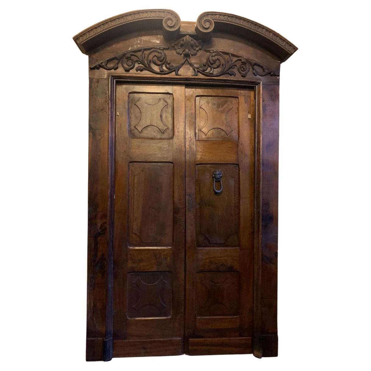 Portoncino doppio in noce con pannelli intagliati, completo di portale, italia