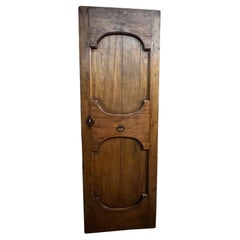 Portoncino in legno di noce ad un battente, con due pannelli intagliati, italia