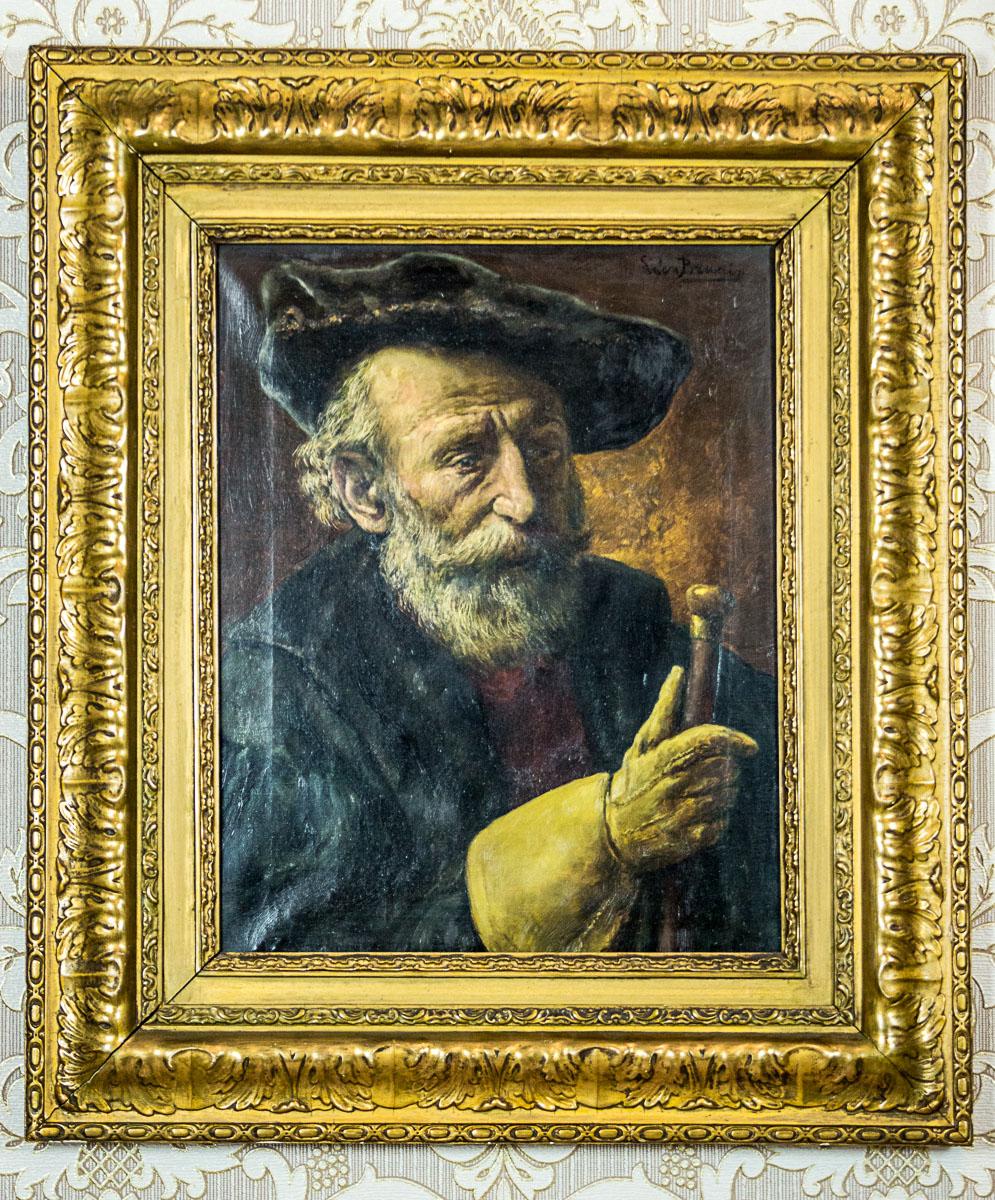 We present you this oil on canvas with a half-length-figure portrait of a man, depicted in en trois quarts. This piece of art is entitled “An Old Man with a Cane.”
The portrait is signed in the upper right corner by a Belgian painter, Leon de