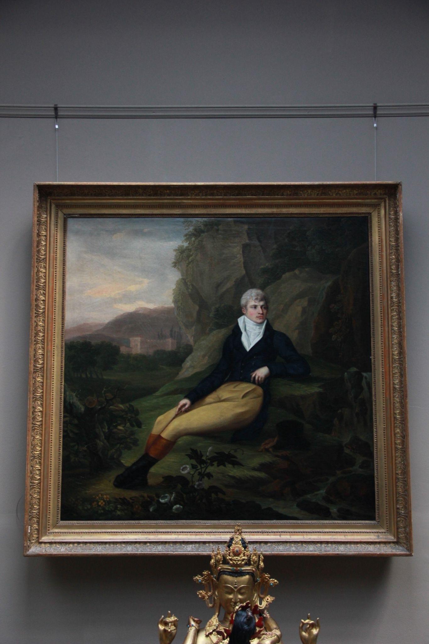 Ein nachdenklicher junger Reisender lehnt inmitten felsiger Klippen und weit entfernter Architektur - seine Kleidung und sein Blick erinnern an die kultivierte Introspektion der Grand Tour. Die Komposition erinnert an Pompeo Batoni, François-Xavier