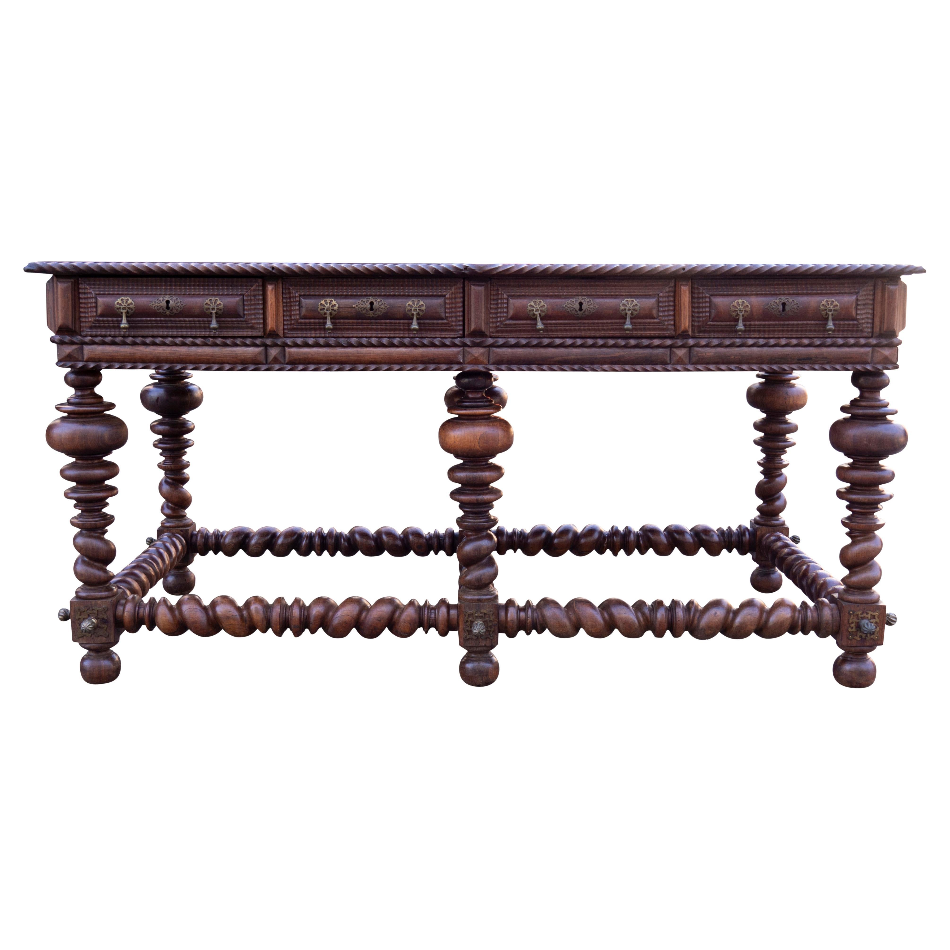 With a single board top with a carved gadrooned edge over a frieze containing four drawers and four false drawers on the reverse. All with beautifully carved details. Boldly turned legs and barley twist stretchers. Brass details overall and on the