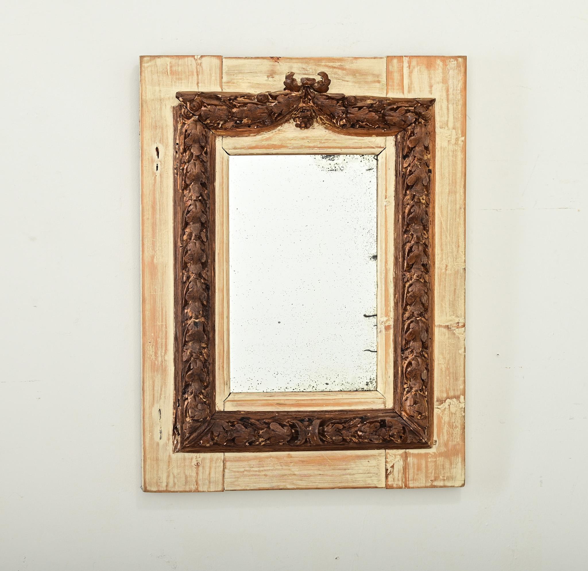 Portuguese 18th century wall mirror with fabulous baroque carvings in oak reinforced by a backboard of painted oak planks in lime-wash effect. Surrounding the original glass plate is a thick border carved to high-relief, in a dense foliate pattern