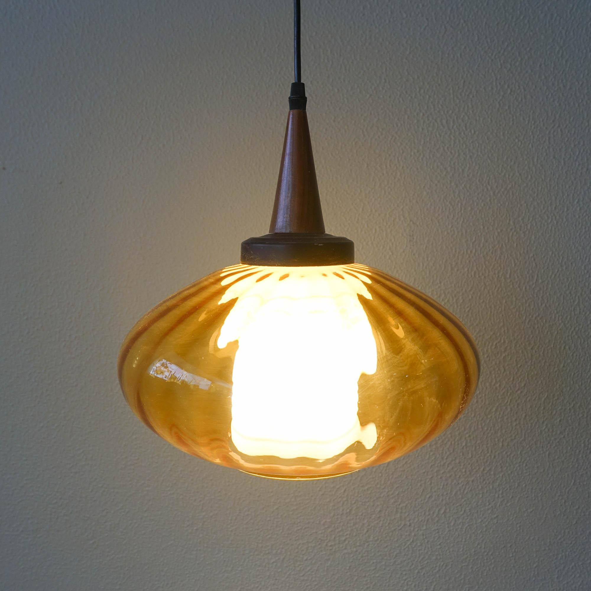 This pendant lamp was designed and produced in Portugal, during the 1950's. It features an amber glass globe and inside a white glass cylinder, which helps to conceal the lamp and spread the light softly. It has the original finishes in metal and