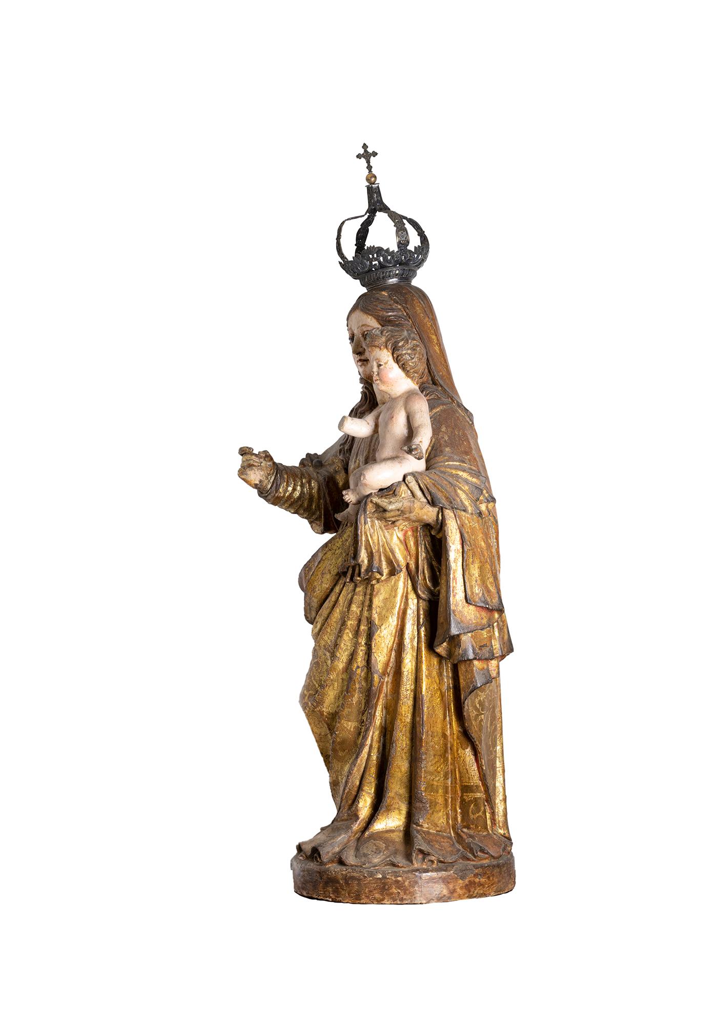 This late 17th-century Portuguese Baroque sculpture in polychromed wood depicts the Madonna holding the Christ Child, carved with exquisite detail and spiritual grace. 
The Virgin is portrayed in flowing Carmelite attire, including a long golden