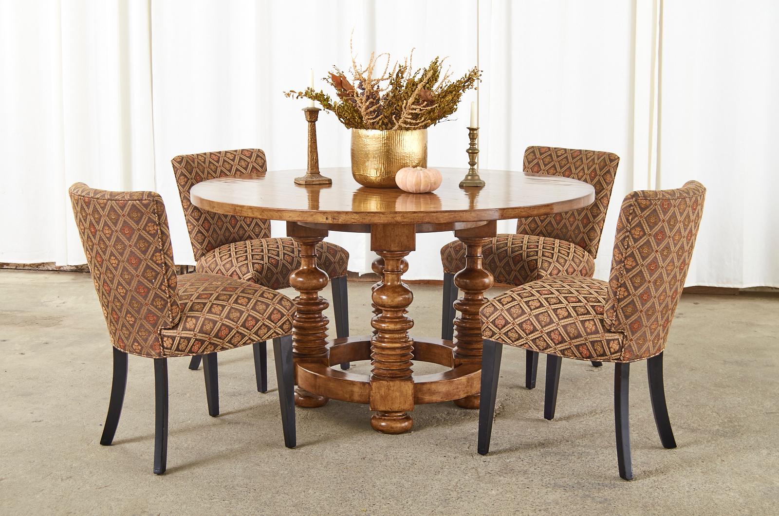 Distinctive round dining table or center table made in the Portuguese baroque taste featuring 4 dramatic large turned legs. The 1.5 inch thick top is attached to the legs with thick, round stretchers on top and bottom of the base. The legs ending