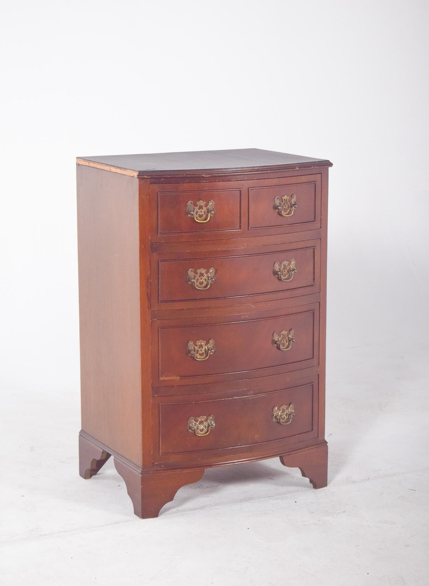 Bedside table with five drawers. Two small drawers are at the top next to the worktop, the three larger ones below, in a classic, balanced design. The furniture has a curved front, finished in a mahogany colour, with metal fittings with ring