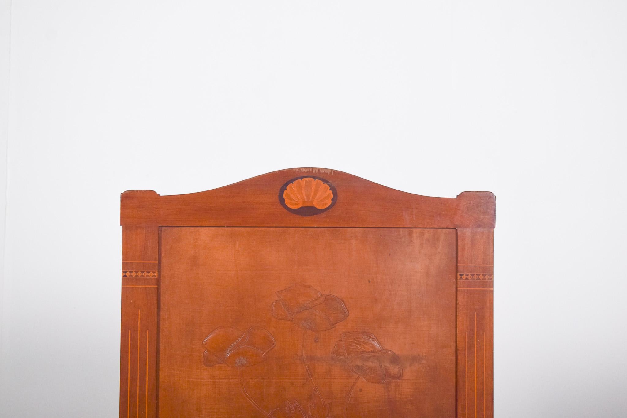 Fireplace front made of carved wood. With floral decoration in bas-relief on the central panel. The piece features delicate work with flowers and foliage, evoking naturalist motifs, very fashionable in the late 19th and early 20th centuries. The