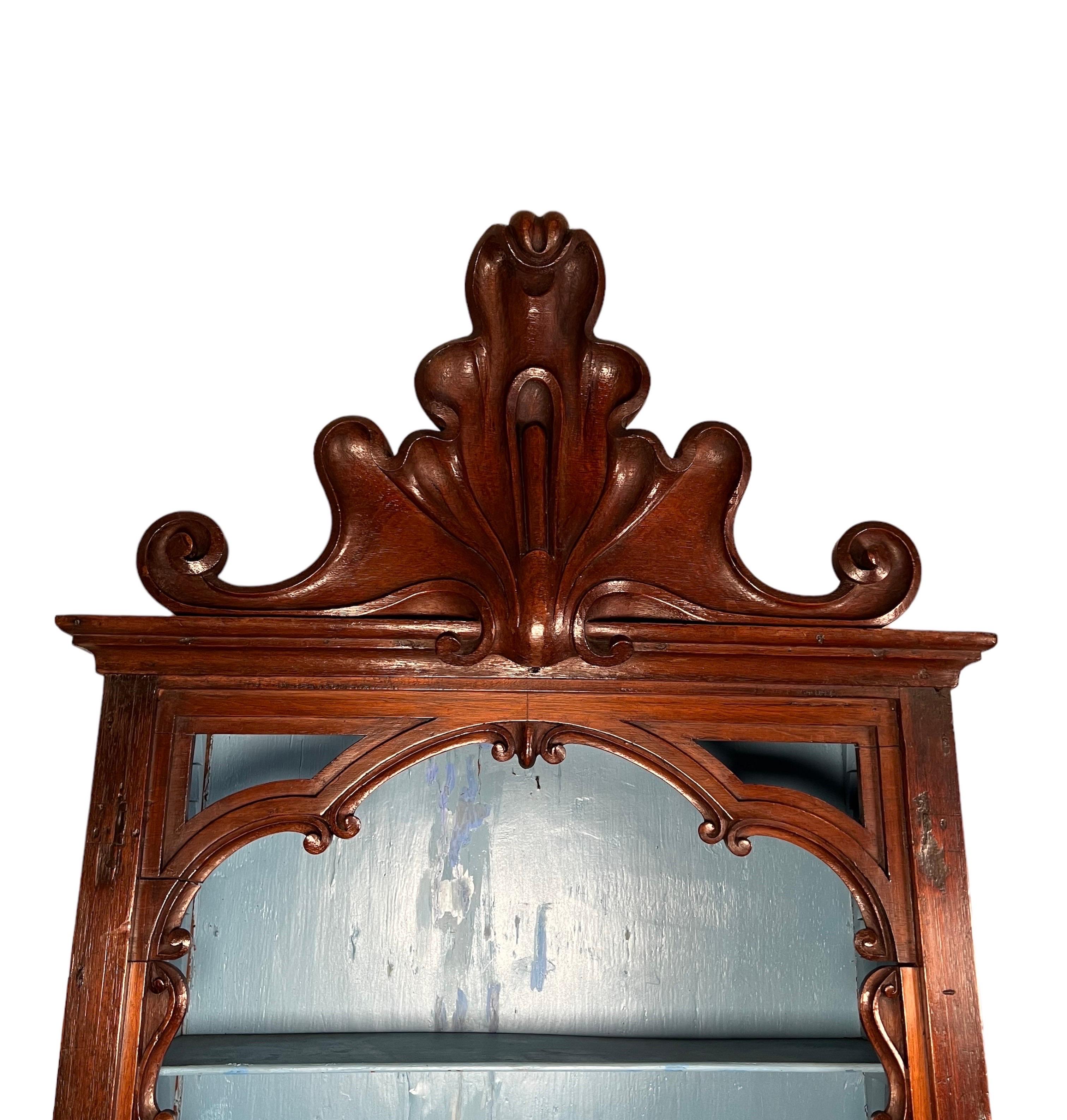 Portuguese, colonial carved hanging shelf. The shelf has two adjustable shelves with a large carved cresting molded base & crown.