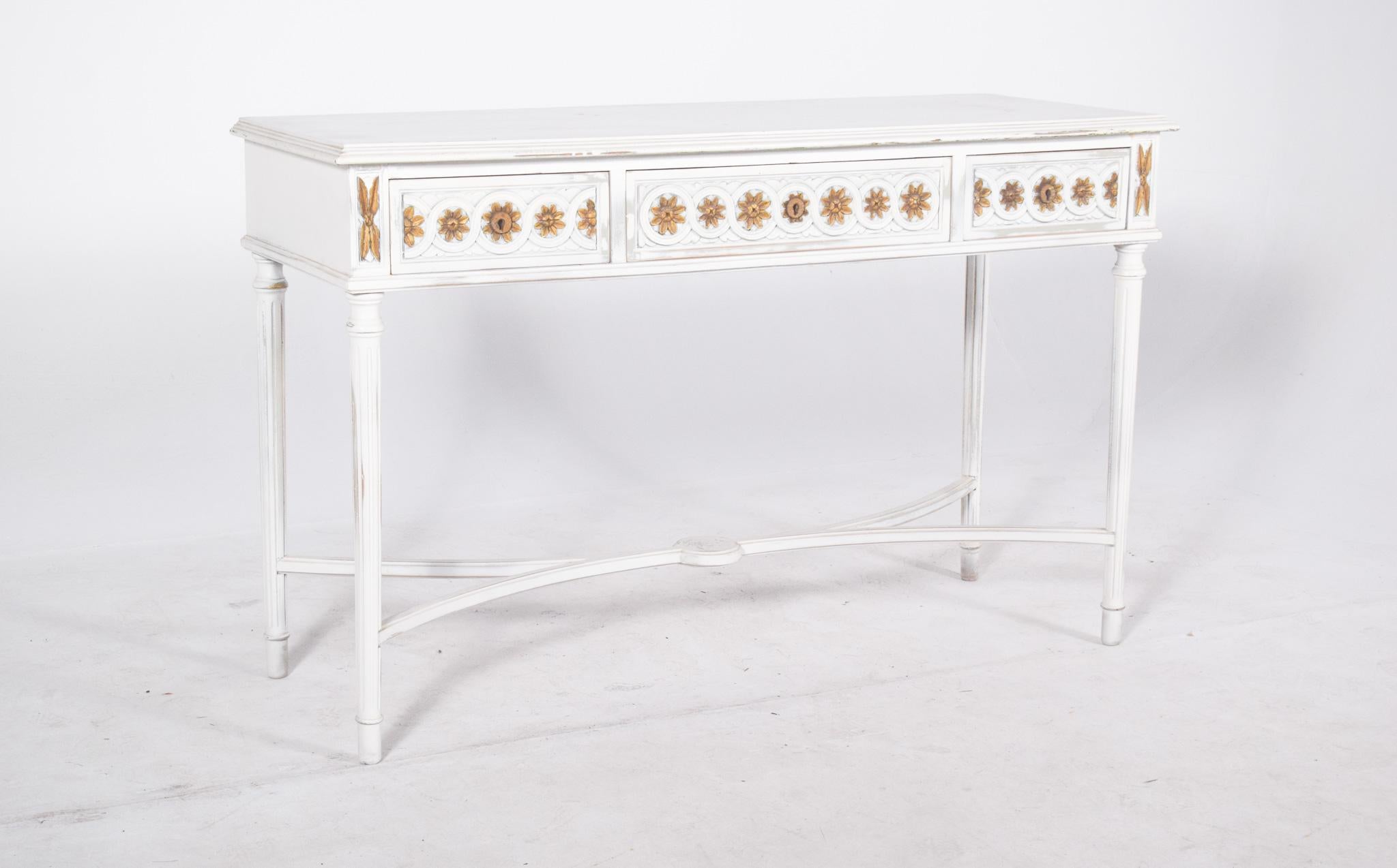 Console painted white with gilding. With an elegant design and balanced proportions, it has three front drawers decorated with delicate carved flowers painted in gold and brown tones, creating a continuous pattern. The sides of the drawers are also