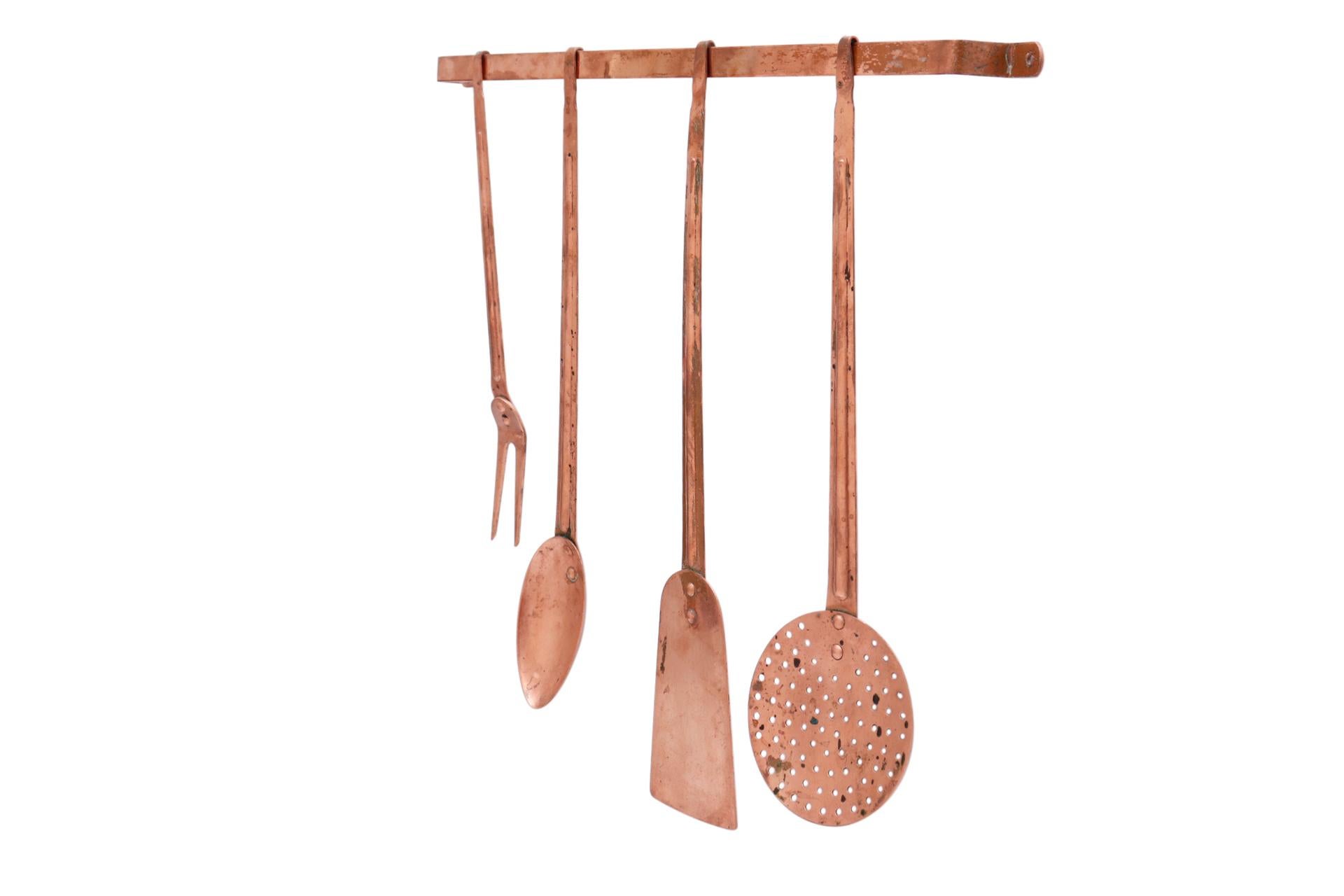 A set of four copper kitchen utensils and support bar, all marked Made in Portugal. Includes a large spoon and fork, spatula and mesh skimmer.