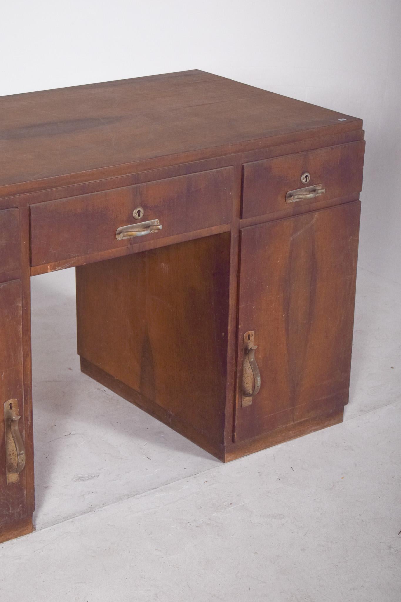 Portuguese desk from the mid-20th century. Robust and functional, typical of public offices or old offices, the desk has two side columns with three drawers each, totalling six drawers. Above each column there is a small opening for a sliding