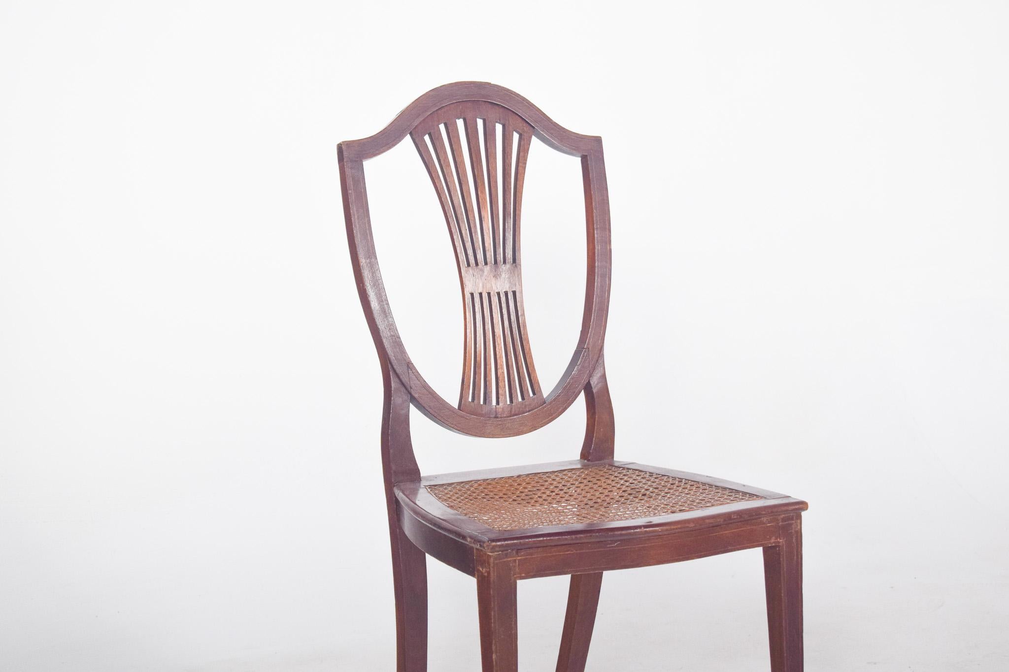 Chaise avec assise en paille. Avec un dossier en forme de bouclier, typique du style Hepplewhite, populaire à la fin du 18e siècle. Le dossier présente des lattes verticales incurvées qui convergent vers le centre, créant ainsi un design léger et