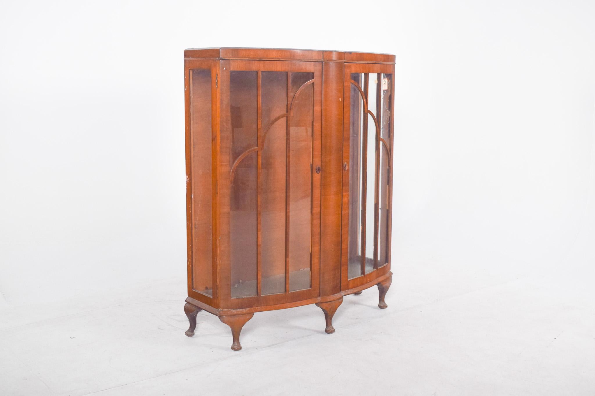 Vitrine à double porte.  Avec une structure légèrement incurvée au centre, un design élégant et des proportions harmonieuses, avec des façades ornées d'impostes en bois qui forment des arcs décoratifs au-dessus des panneaux de verre. Il repose sur