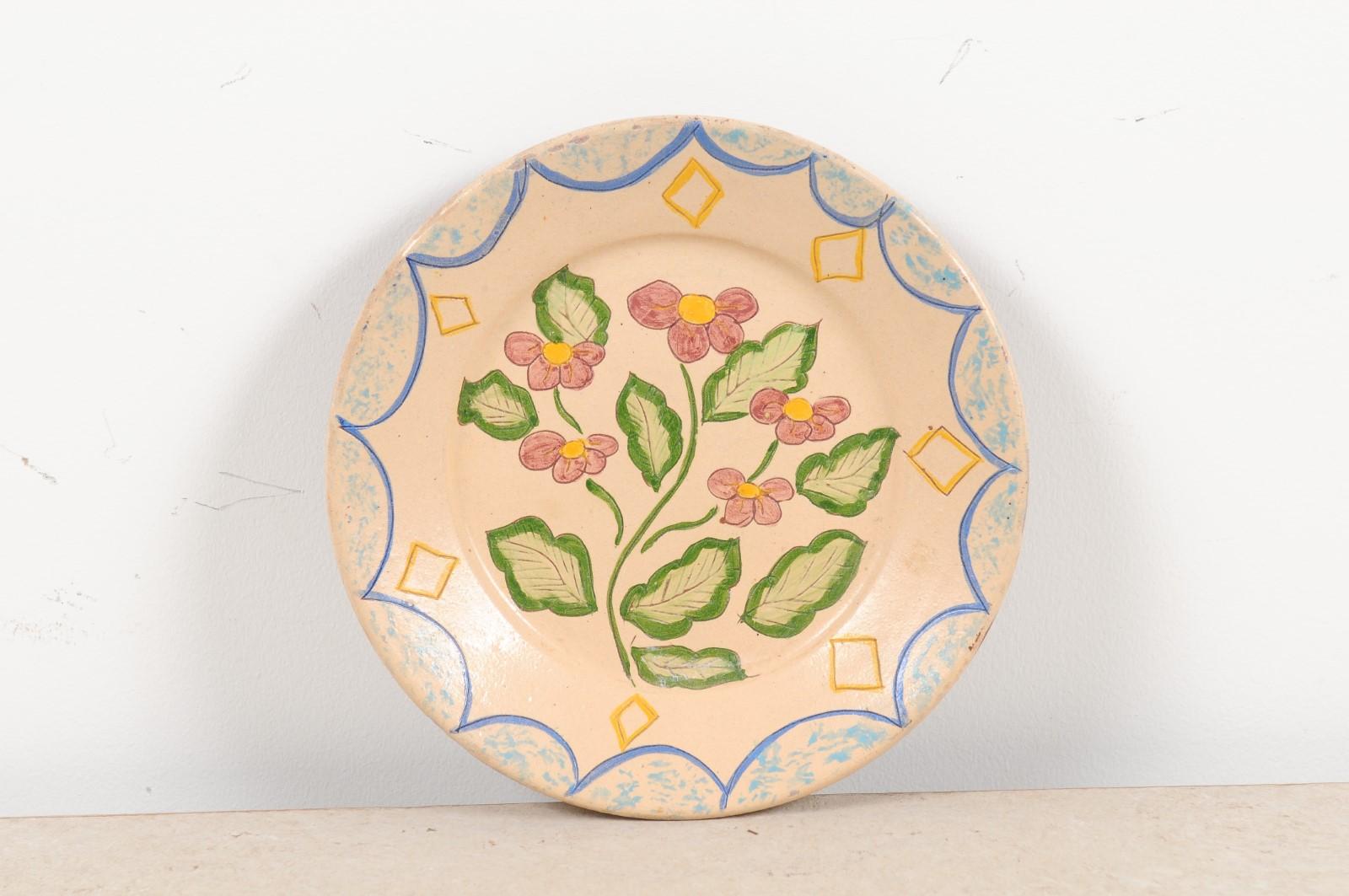 A Portuguese early 20th century painted clay pottery plate from Sao Pedro do Corval, with floral decor. Created in one of the largest Portuguese pottery centers during the early years of the 20th century, this painted clay plate charms us with its
