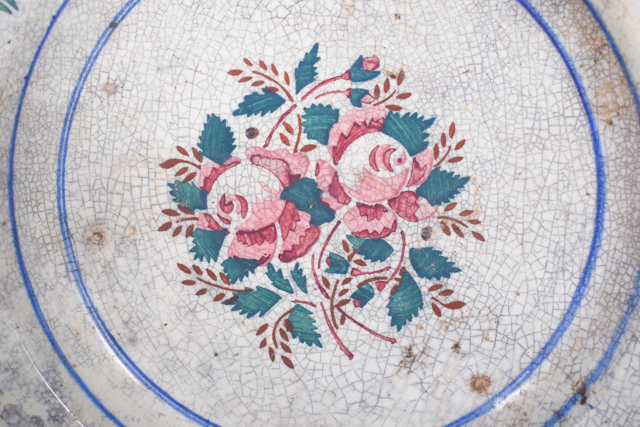 Portugiesische Schale aus Steingut, hergestellt in Coimbra. Polychrome Dekoration, mit einem zarten floralen Motiv in der Mitte, von Rosen in Schattierungen von rosa und grün und braunen Blättern, umgeben von zwei blauen Friesen, die die