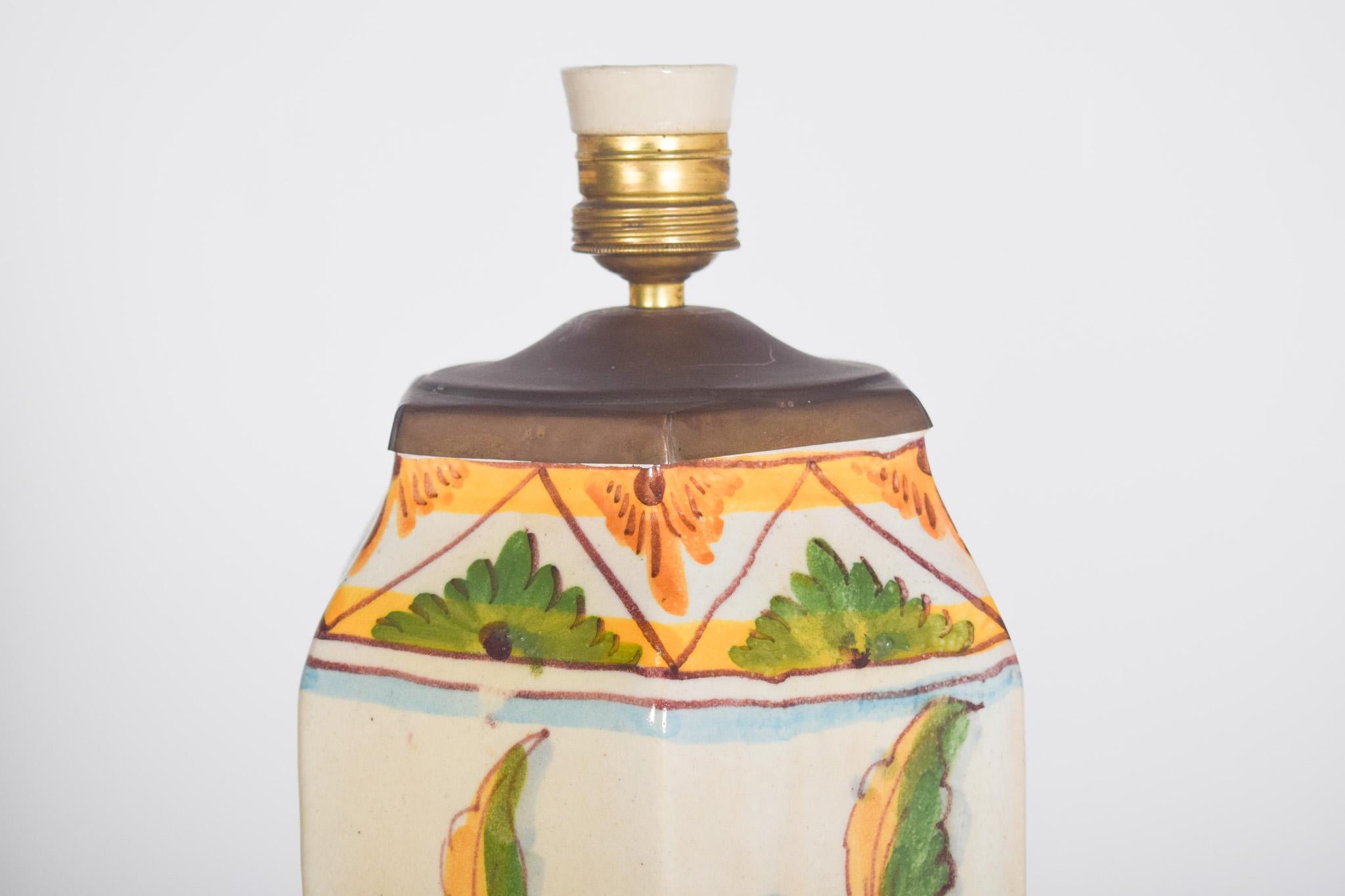 Lampe en faïence portugaise de Sant'Anna. Décoration polychrome avec des motifs floraux et végétaux.
De forme hexagonale, il présente une base aux tons clairs, sur laquelle se détachent de délicats motifs floraux peints à la main. Les fleurs et les