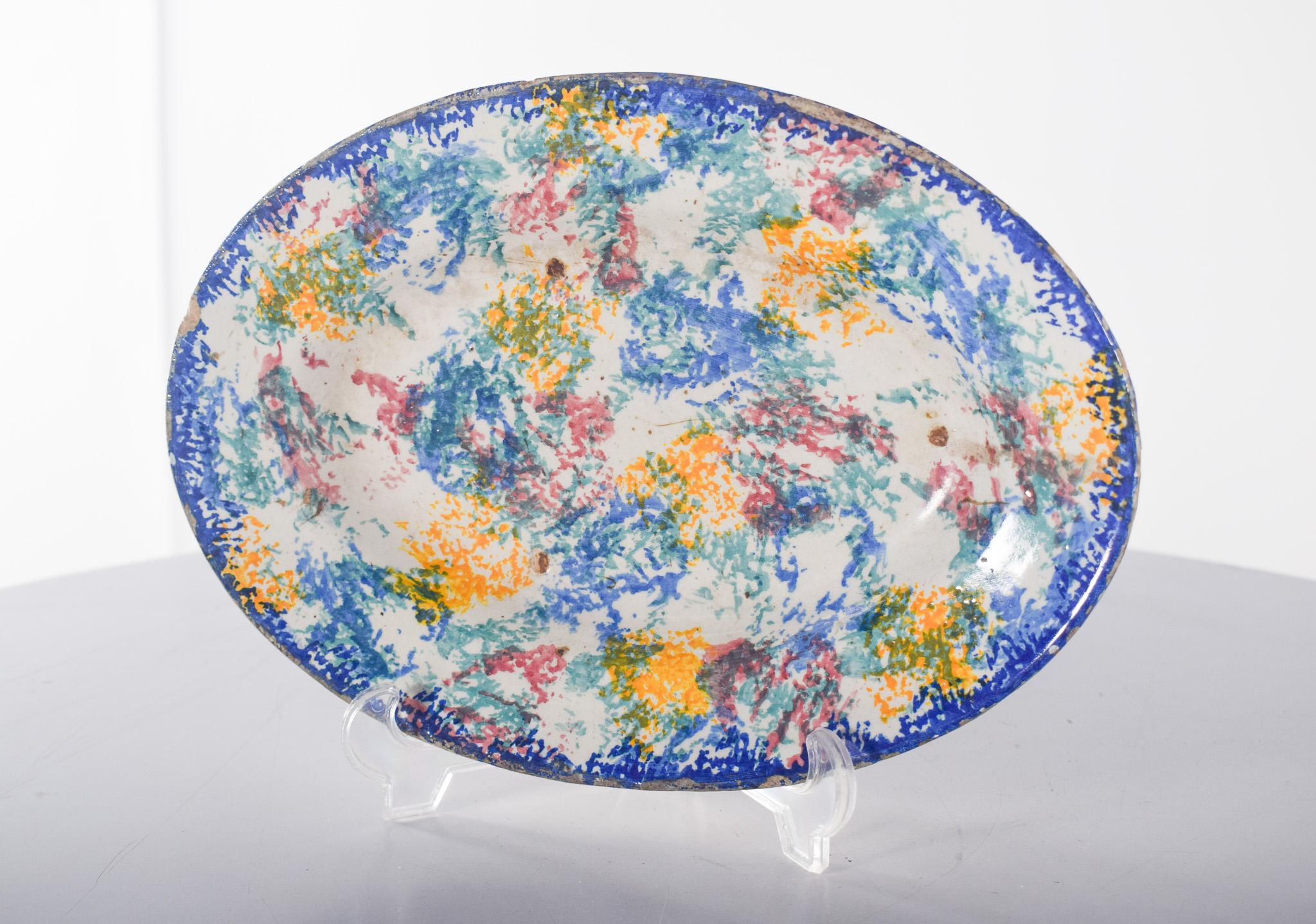Portuguese earthenware platter. Sponged polychrome decoration in blue, yellow, green and red.
The rim of the dish is outlined in an intense blue colour, creating a striking contrast with the central surface, full of abstract and irregular patterns.