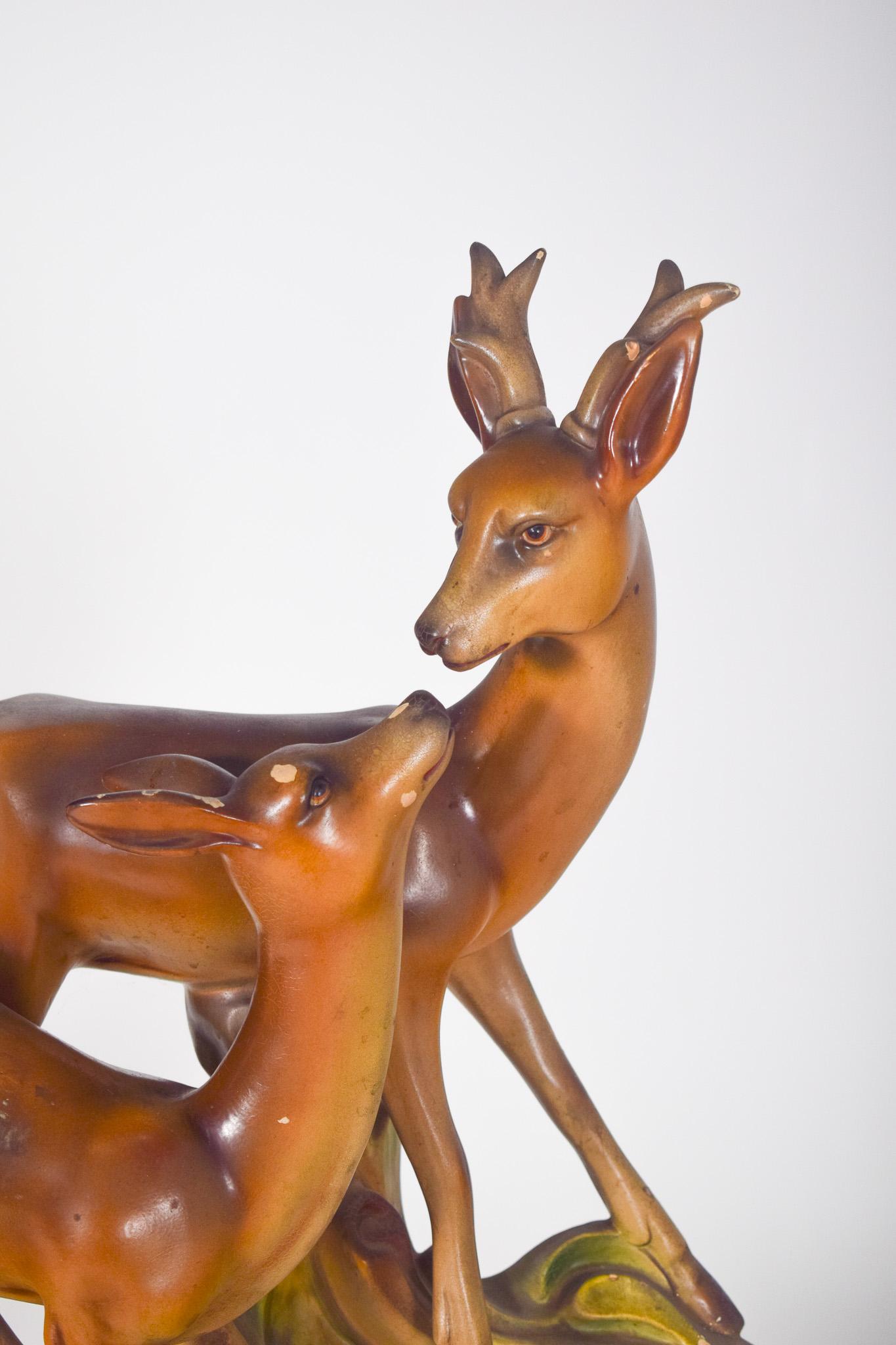 Sculpture en orfèvrerie représentant deux gazelles. Décoration polychrome dans les tons de brun et de vert. La plus grande gazelle a des cornes et une posture droite, tandis que la plus petite, sans cornes, le regarde depuis une position plus basse,