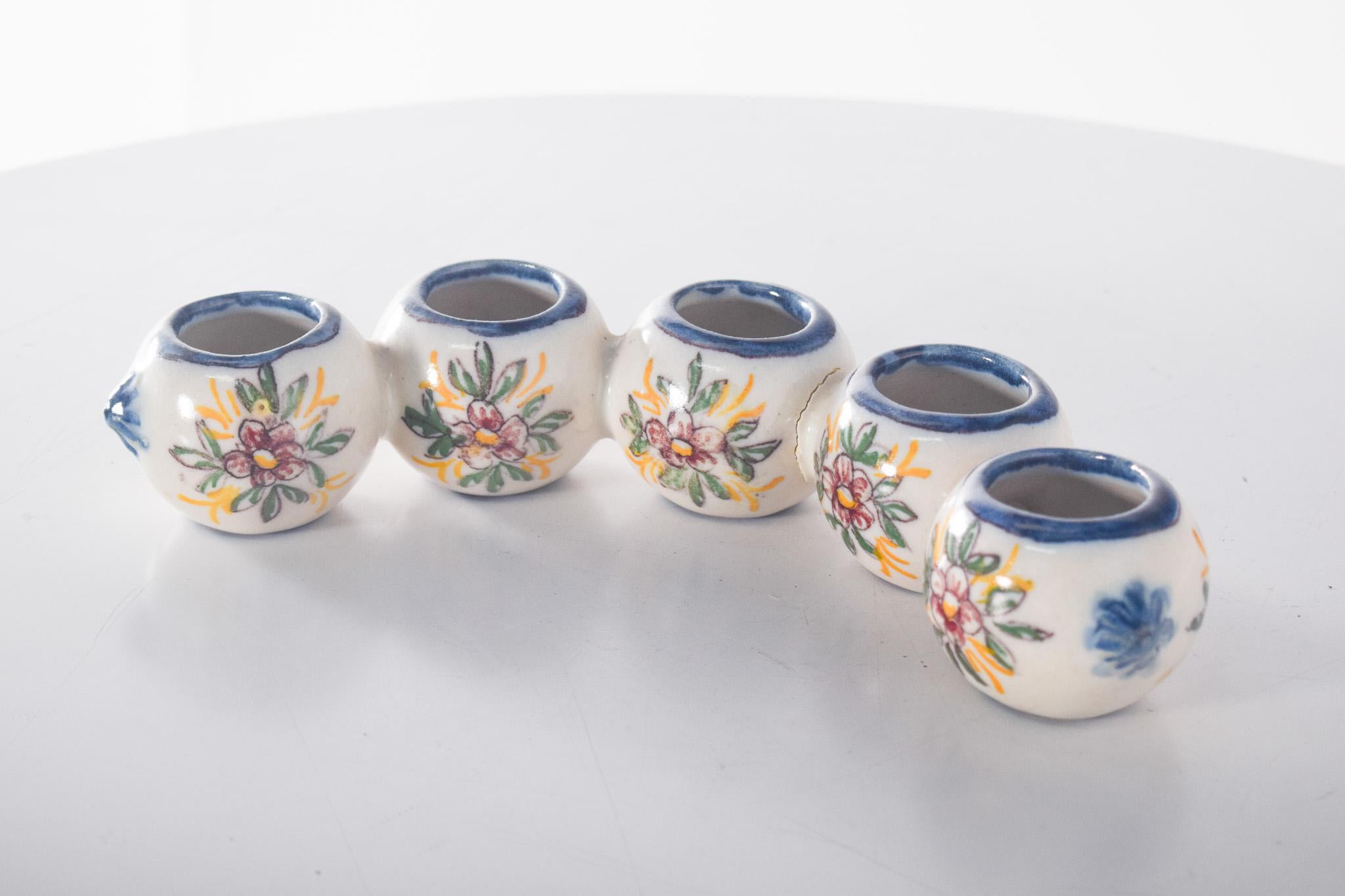 Portacandele in maiolica portoghese di Sant'Anna. Decorazione policroma, composta da cinque piccoli contenitori interconnessi, ciascuno con un'apertura superiore per ospitare piccole candele. La decorazione presenta motivi floreali dipinti a mano in