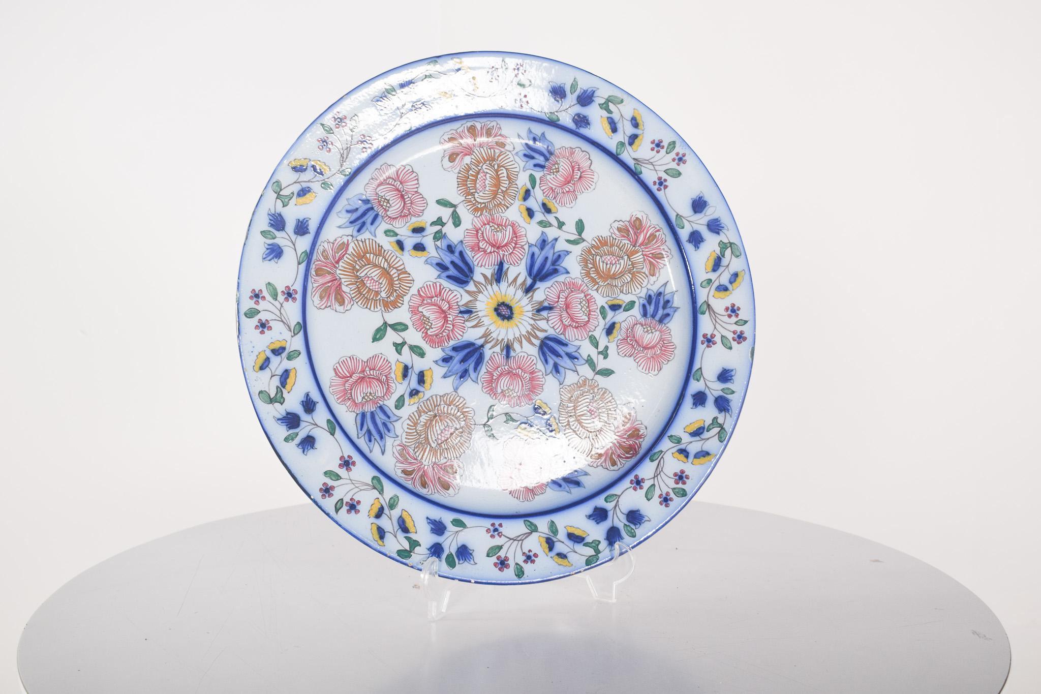 Dish in Portuguese Estatuária faience from Coimbra. Polychrome decoration with a colourful floral pattern inspired by traditional handmade ceramics. The dish has a white background with details in blue, red, yellow and green, forming a harmonious