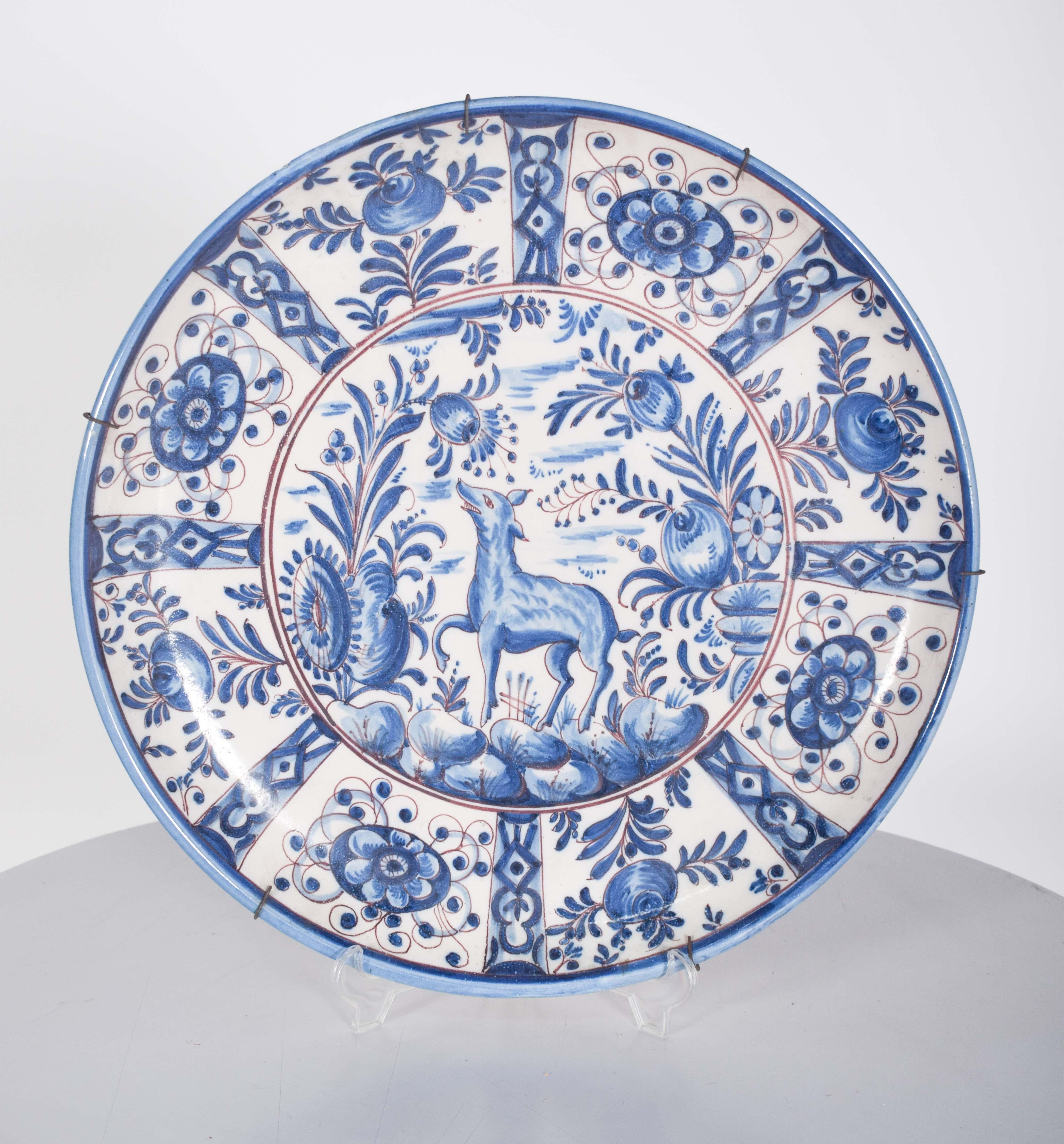Ce grand plat à manger portugais de Sant'Anna est une pièce raffinée qui célèbre la tradition de la céramique artisanale portugaise. Décorée avec minutie, elle présente des motifs floraux et végétaux dans des tons de bleu et de vigne, qui se