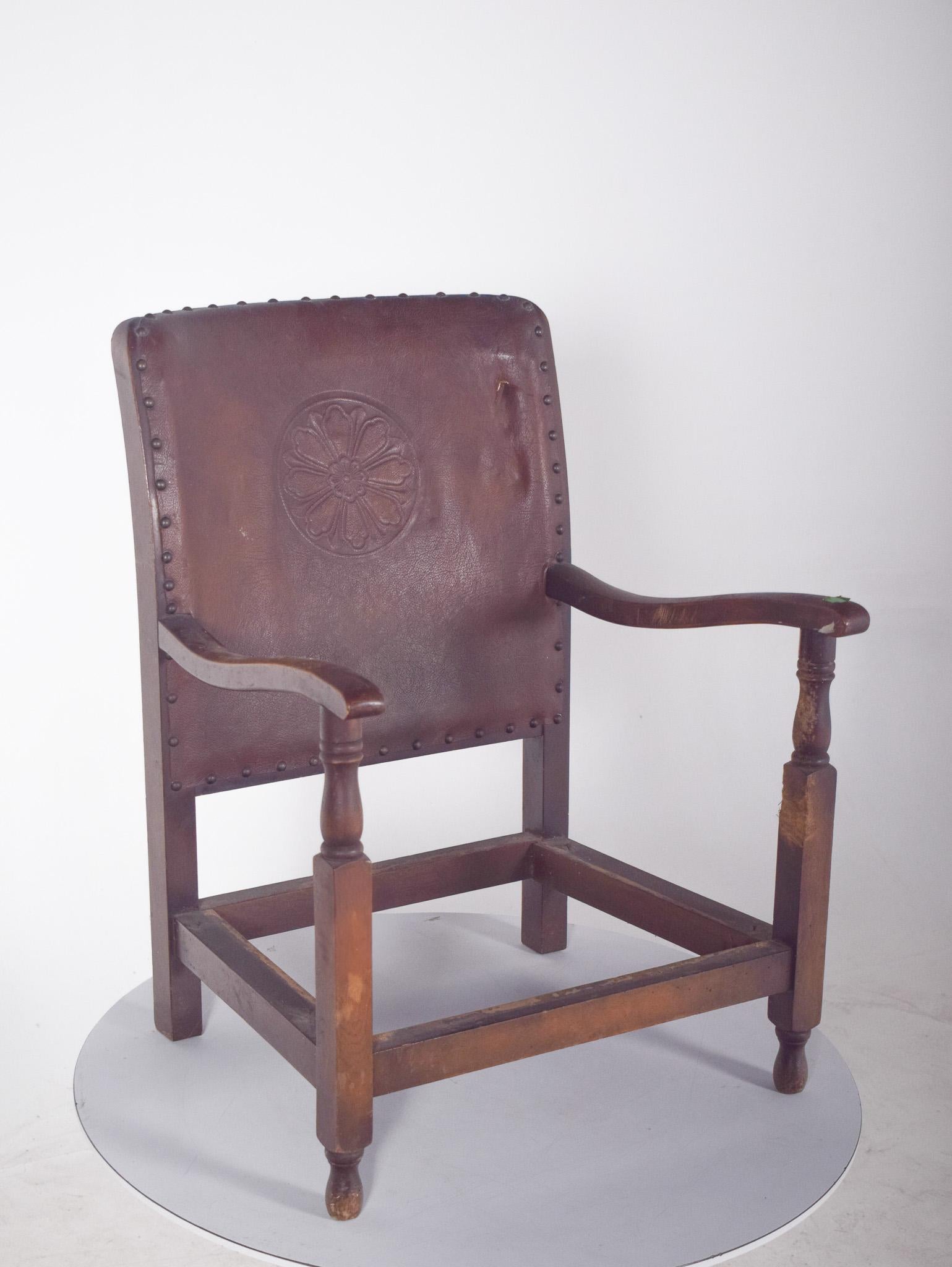 Chaise basse avec dossier en cuir et sans assise. Le dos en cuir est gravé d'une fleur stylisée au centre. Le dossier est entouré de clous métalliques, ce qui renforce non seulement la fixation du cuir, mais aussi le caractère décoratif de la pièce.
