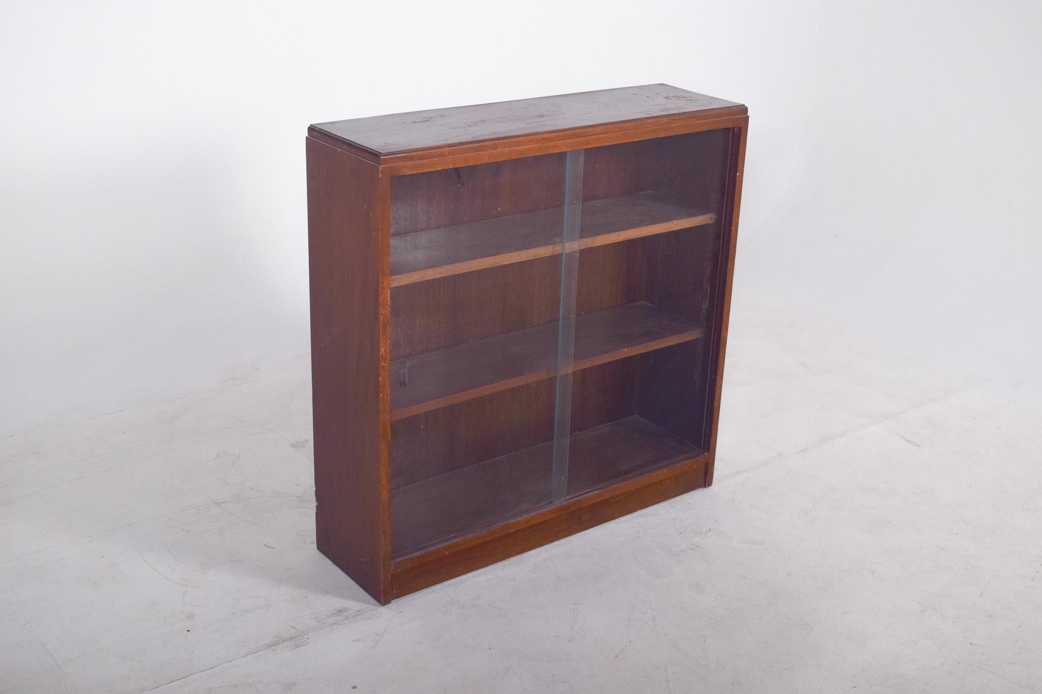 Low display case with two shelves. Simple and functional in design, the unit has a rectangular shape with two fixed internal shelves, creating three levels of storage or display. The front is closed by two sliding glass doors, allowing good