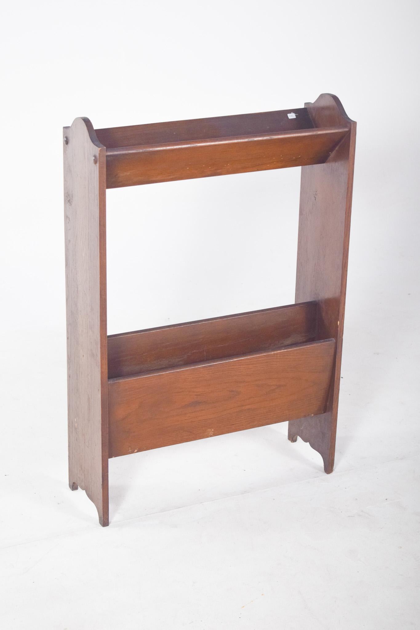 Oak magazine rack. Simple rectangular structure, consisting of two flat sides with a smooth cutout at the top and bottom, with a light decorative detail. It has two compartments: a deeper lower one, suitable for storing magazines, newspapers or