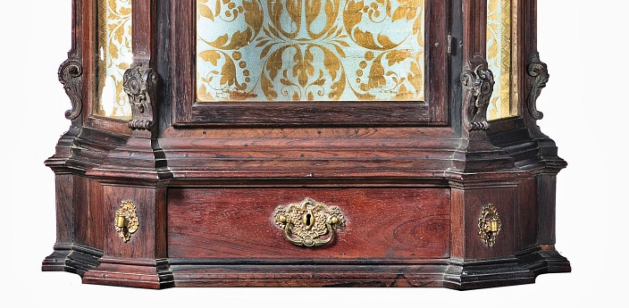 Portuguese Oratory
18th century. 
Carved wood. 
Palisander wood
Decoration with interrupted pediments, scrolls, floral motifs, plant windings and pilasters. 
Door and glazed edges with a drawer. 
Gold painted interior. 
Dimensions: (oratory)