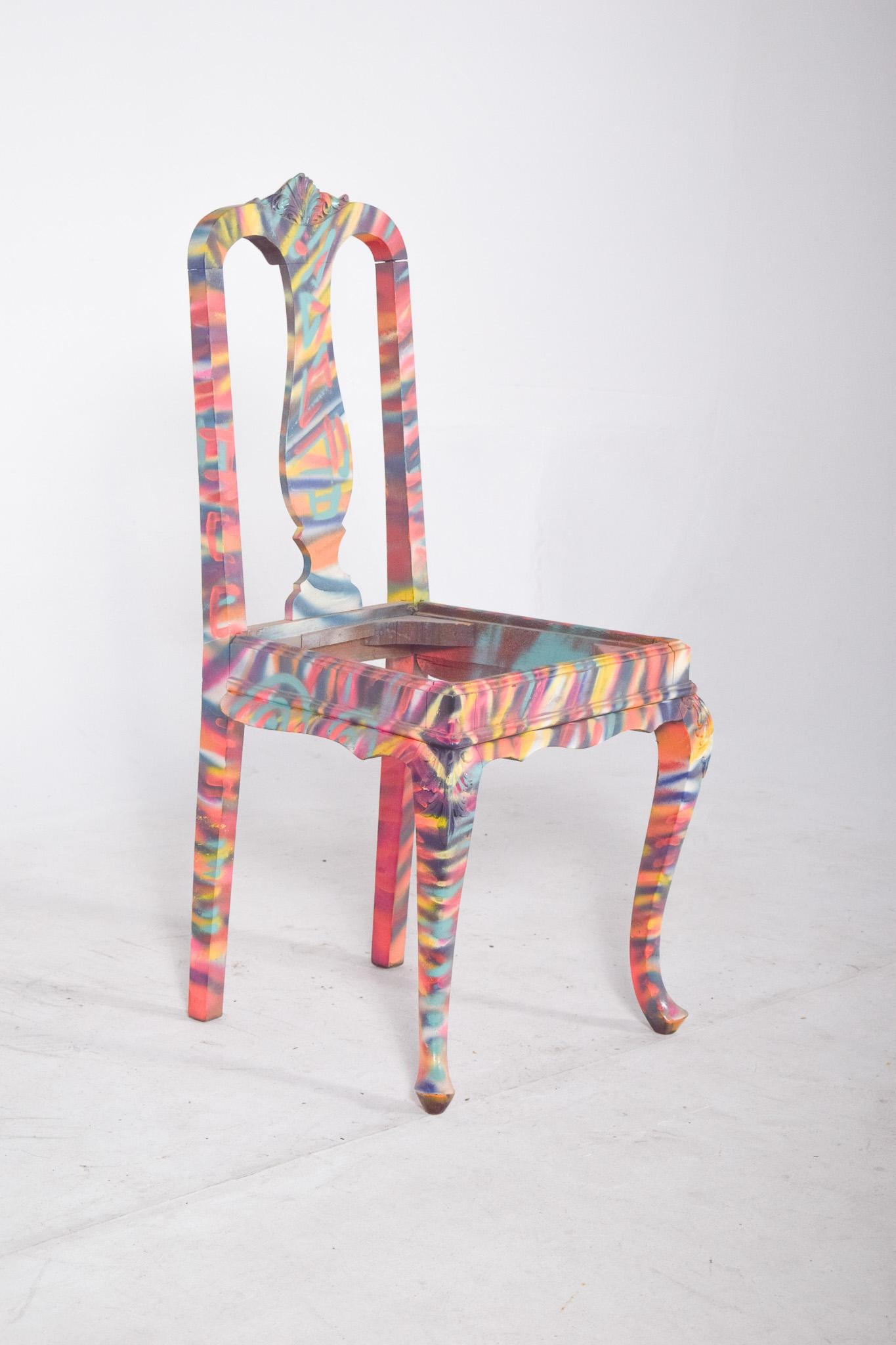 Chaise de salle à manger peinte. Avec des sculptures décoratives sur le bord supérieur, elle a été décorée avec de la peinture multicolore contemporaine. Le bas de l'œuvre est recouvert d'une base vibrante où prédominent les nuances de rose, de