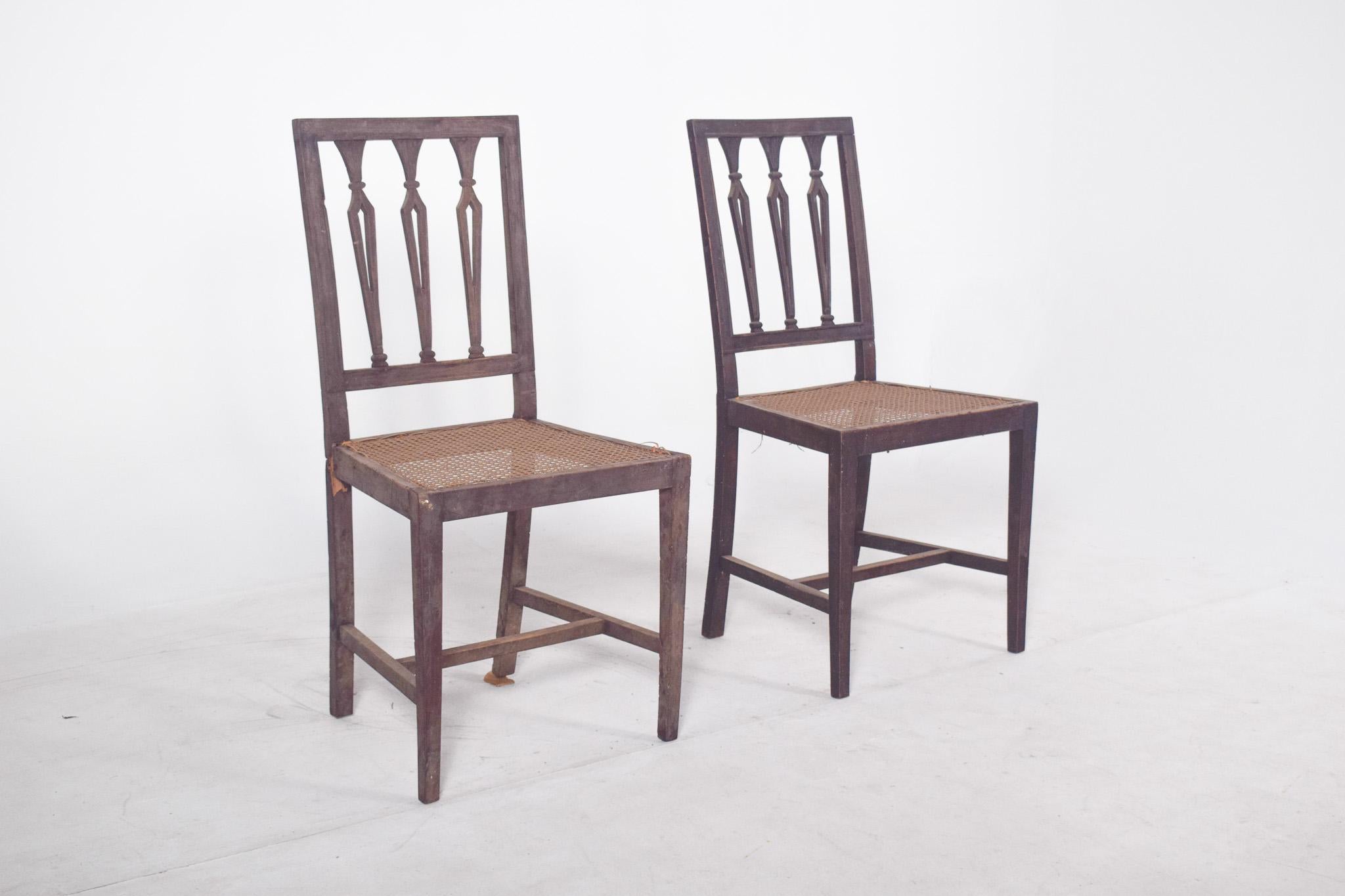 Coppia di sedie con seduta in paglia. Con uno schienale alto, un design sobrio e una struttura dritta, ispirata all'estetica neoclassica con elementi semplici. Lo schienale presenta tre doghe verticali con perforazioni geometriche che conferiscono