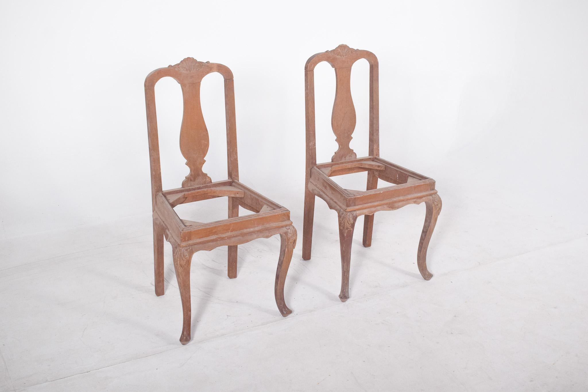 Coppia di sedie da pranzo con gambe ricurve. Lo schienale presenta un taglio classico con un cartiglio centrale a forma di violino, delimitato da una cornice dolcemente ondulata, sormontata da un delicato intaglio a conchiglia stilizzato. Le gambe