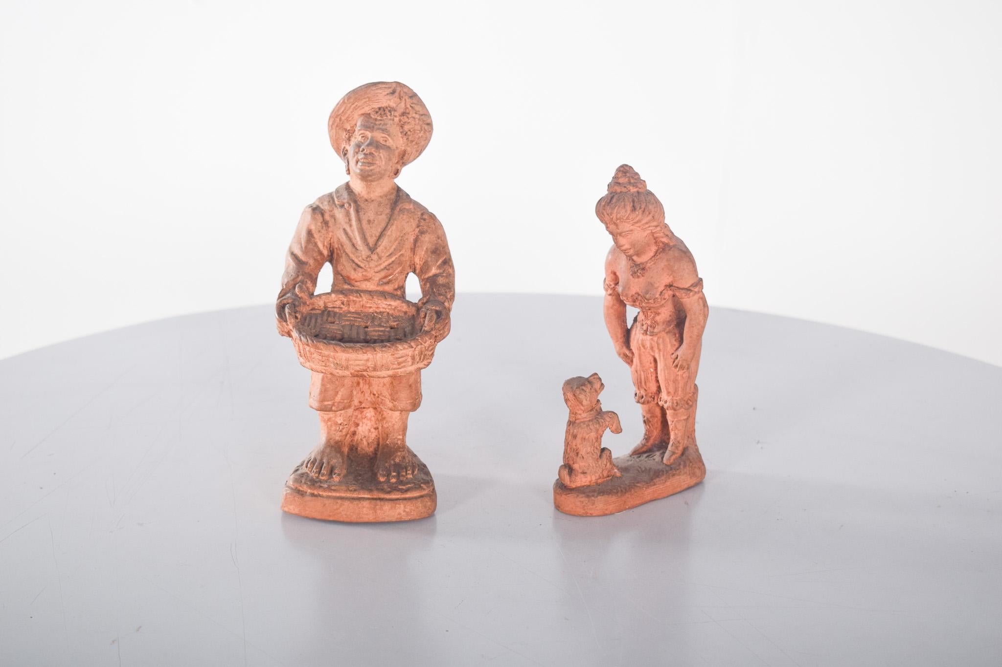 Coppia di sculture in terracotta. Opere d'arte dettagliate che evocano scene di vita quotidiana con un tocco rustico e tradizionale. Le figure raffigurano diversi personaggi: un contadino, forse un venditore ambulante, che tiene in mano un grande