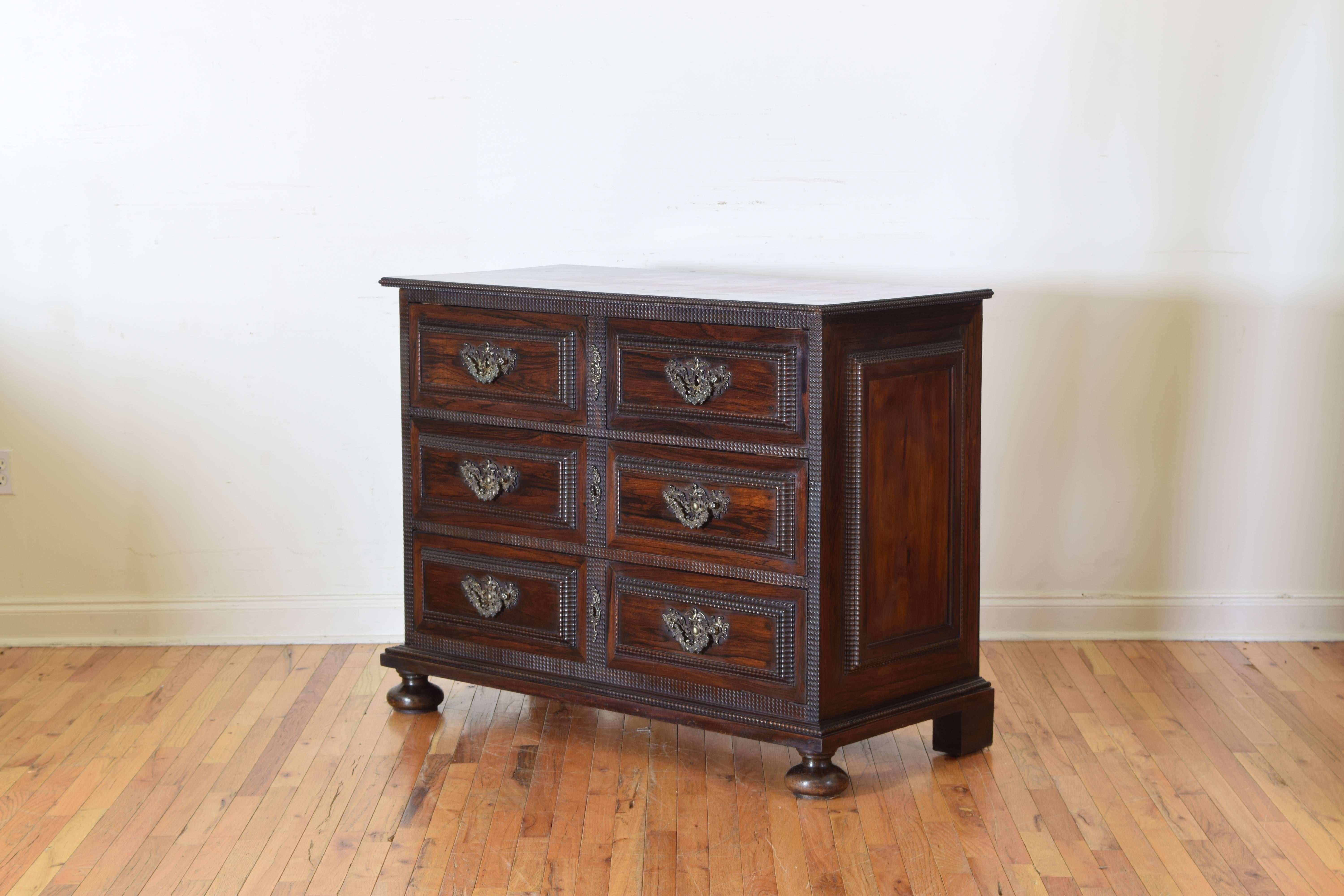 Constructed entirely of rosewood, the rectangular top with a ripple molded edge above a conforming case housing two small drawers over two large drawers all with raised panels with ripple molded edges, pierced bronze mounts in relief, the sides also