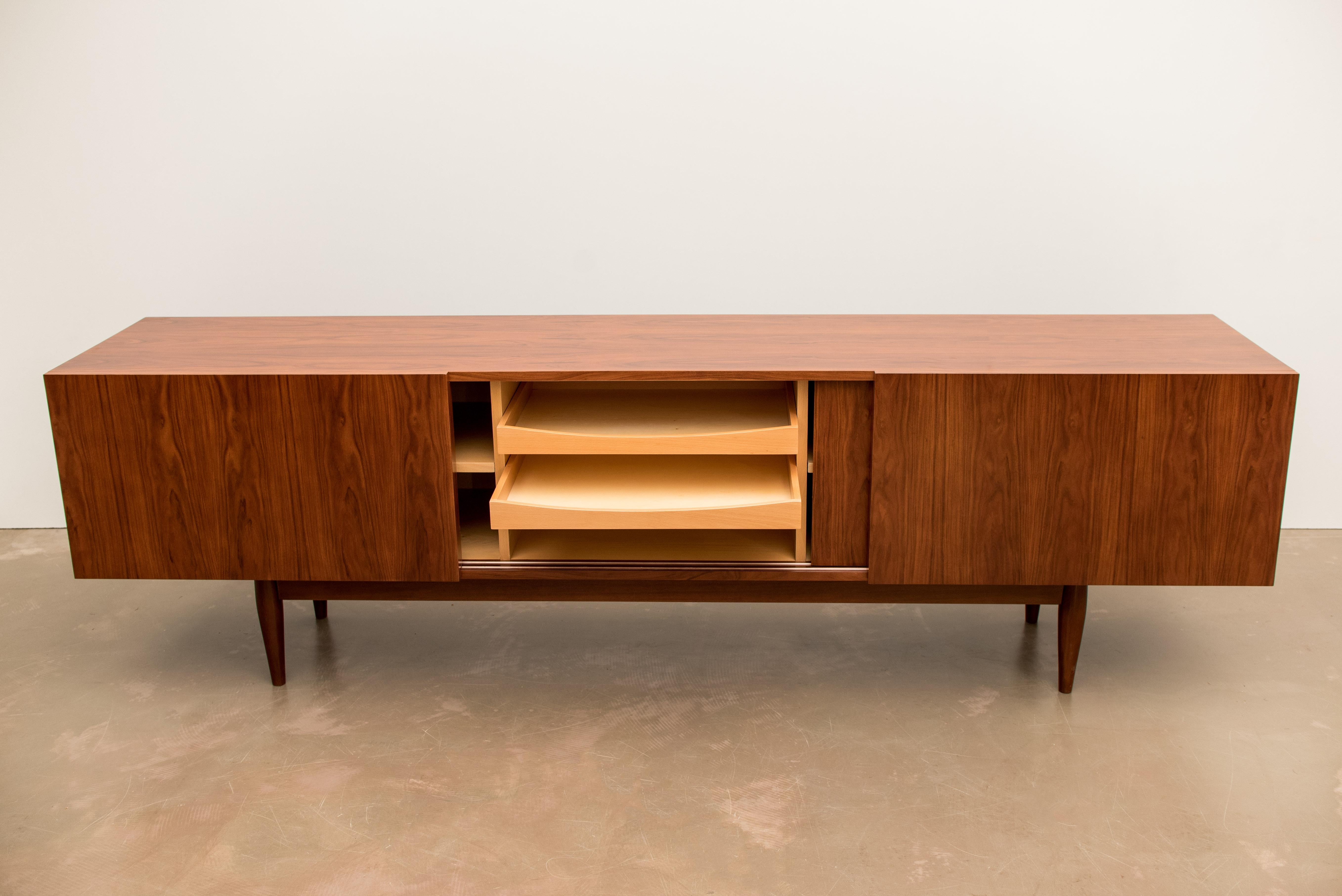This wide sideboard is made of rosewood and features sliding doors opening to internal compartments and drawers.