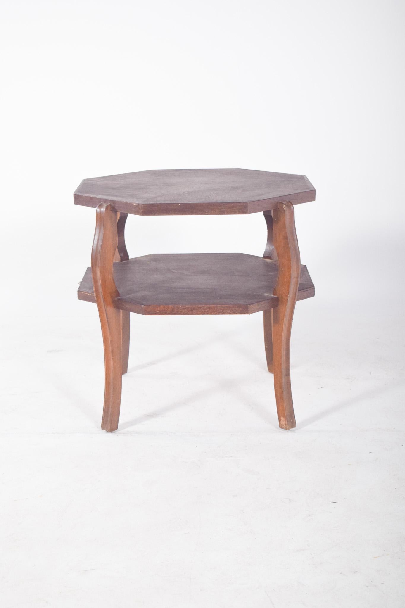 Oak coffee table. With an octagonal design and a dark finish, it has two shelves, top and bottom, ideal for supporting decorative objects or for functional use next to sofas and armchairs. The curved cabriolet-style legs give the piece a classic and