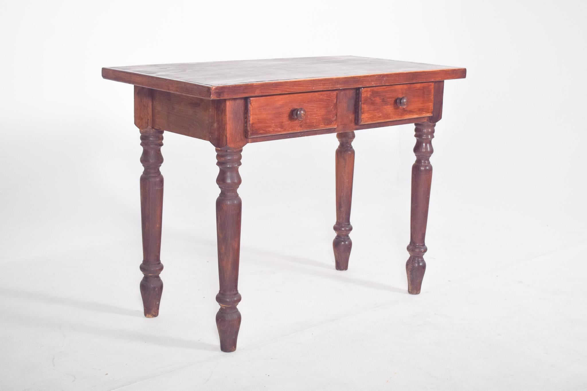 Pine kitchen table. With a flat rectangular top, simple edges and a sturdy structure, it is made up of four turned legs with profile shafts alternating between cylindrical and conical segments, fixed directly to the bottom brace. The front features