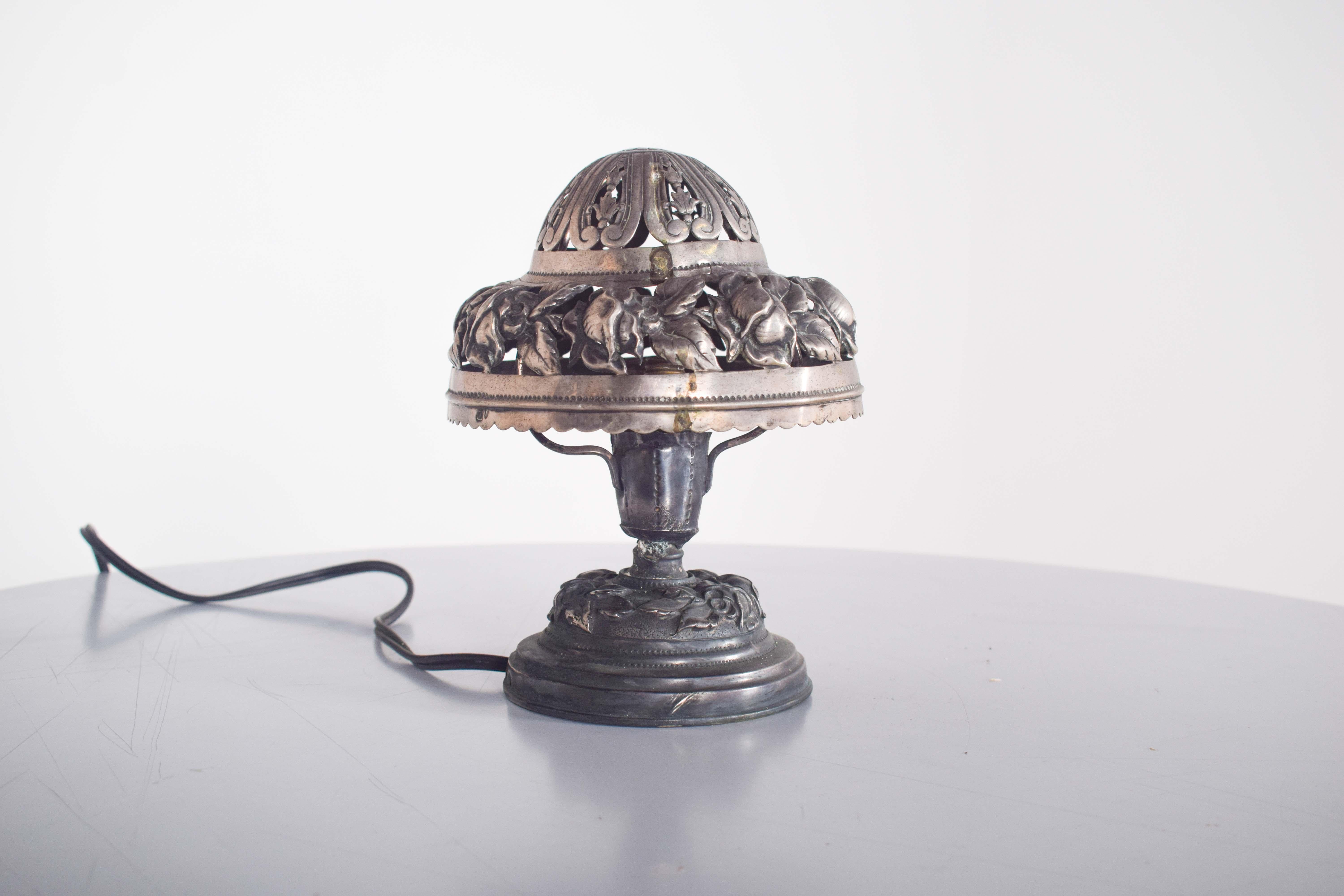 Una piccola e affascinante lampada portoghese in argento, disegnata a forma di fungo con una base rotonda. La lampada è splendidamente decorata con intricati motivi di fiori e foglie sia sul paralume che sulla base, aggiungendo un tocco di eleganza