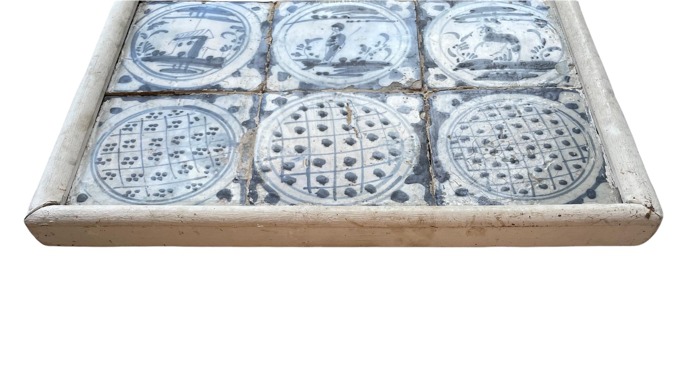 This is a small wood framed mural of “azulejos”or white and blue tiles. It consists of three rows of tiles and each one has three tiles. The first row depicts from left to right a star, a bird and a branch of flower. The second one depicts a rural