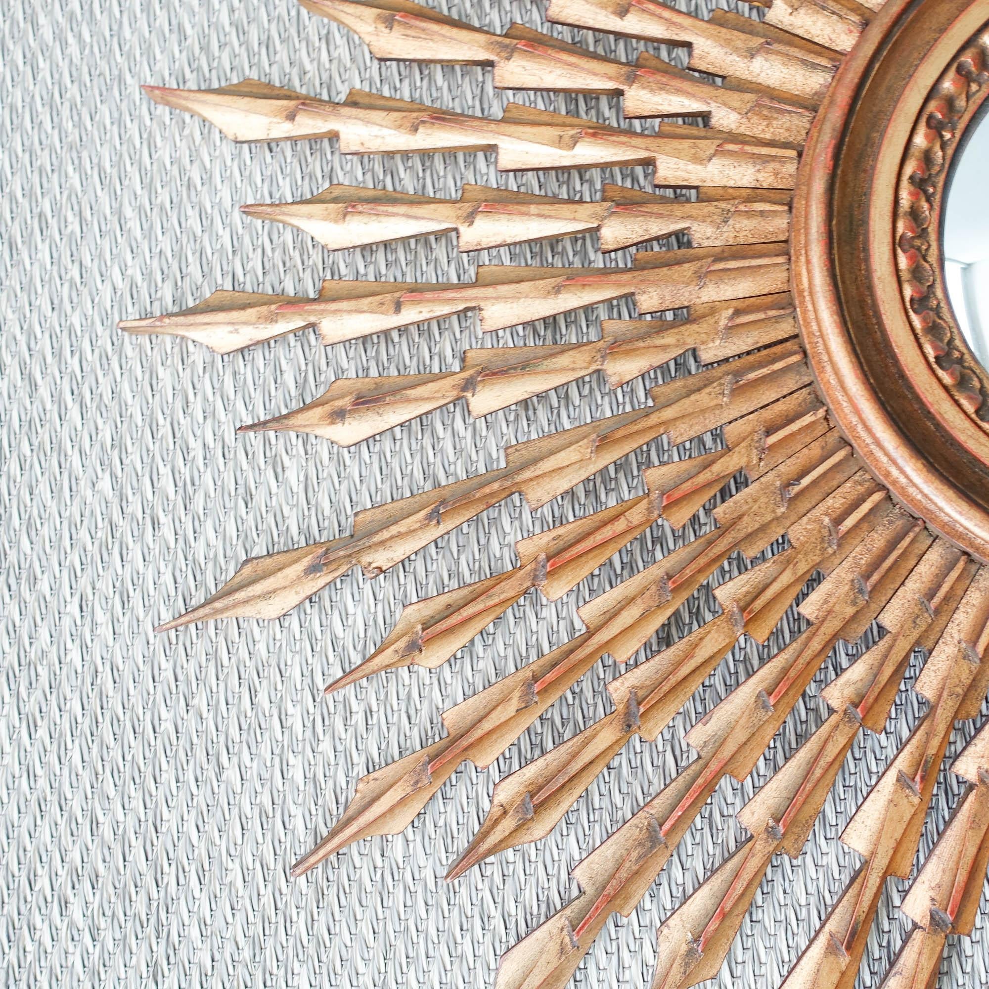 Dieser Spiegel mit Sonnenschliff wurde in den 1950er Jahren in Portugal entworfen und hergestellt.
Es hat einen geschnitzten Rahmen aus vergoldetem Holz, der aus einer Schicht von langen und kürzeren Strahlen besteht. Der Ring, der den zentralen