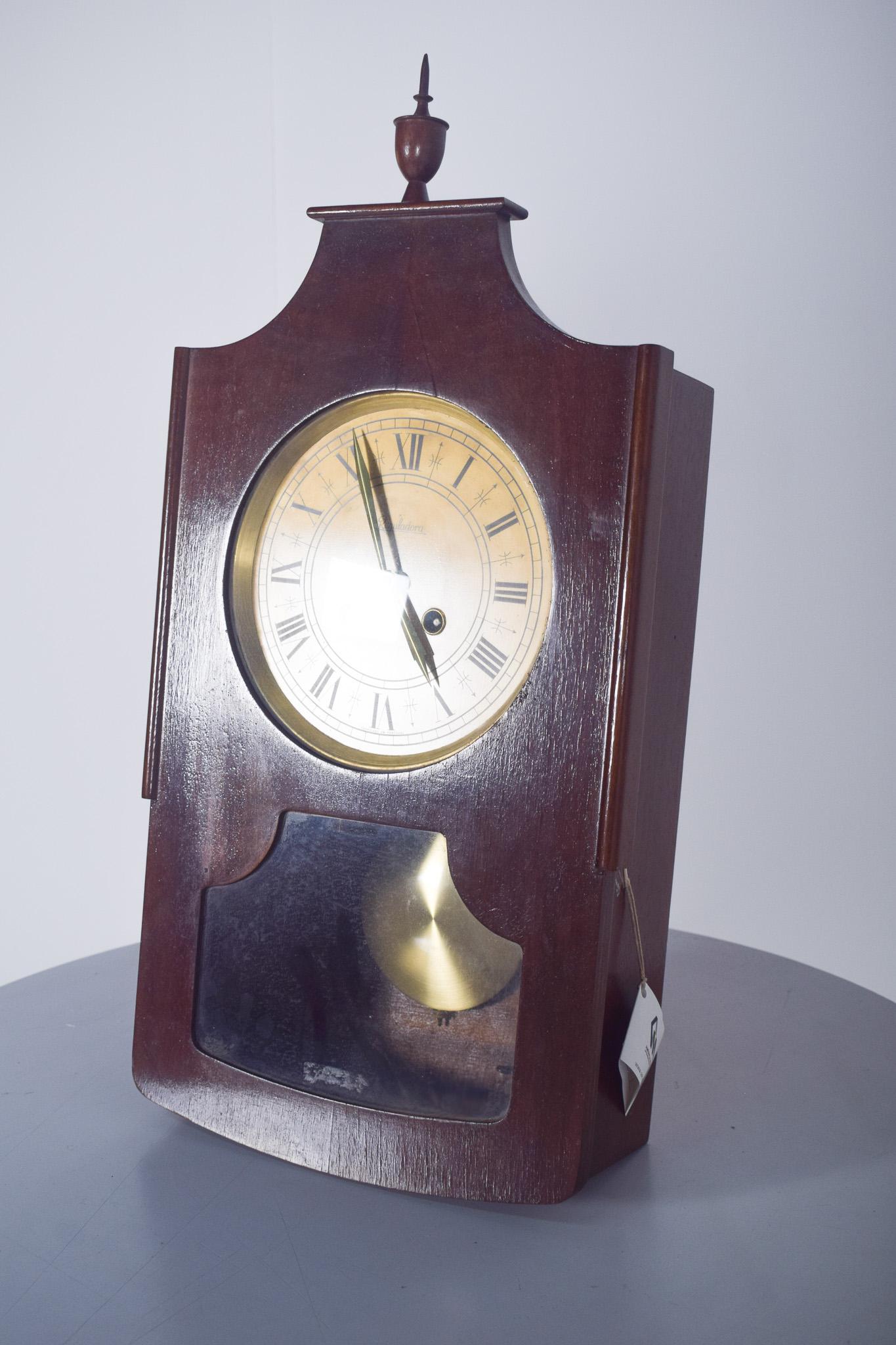 Portuguese wall clock, Fábrica Reguladora, SARL. This clock from Fábrica Nacional de Relógios, Reguladora SARL, Vila nova de Famalicão, has a wooden frame and a gold dial. It has a classic design, with a rectangular shape and curved top, decorated