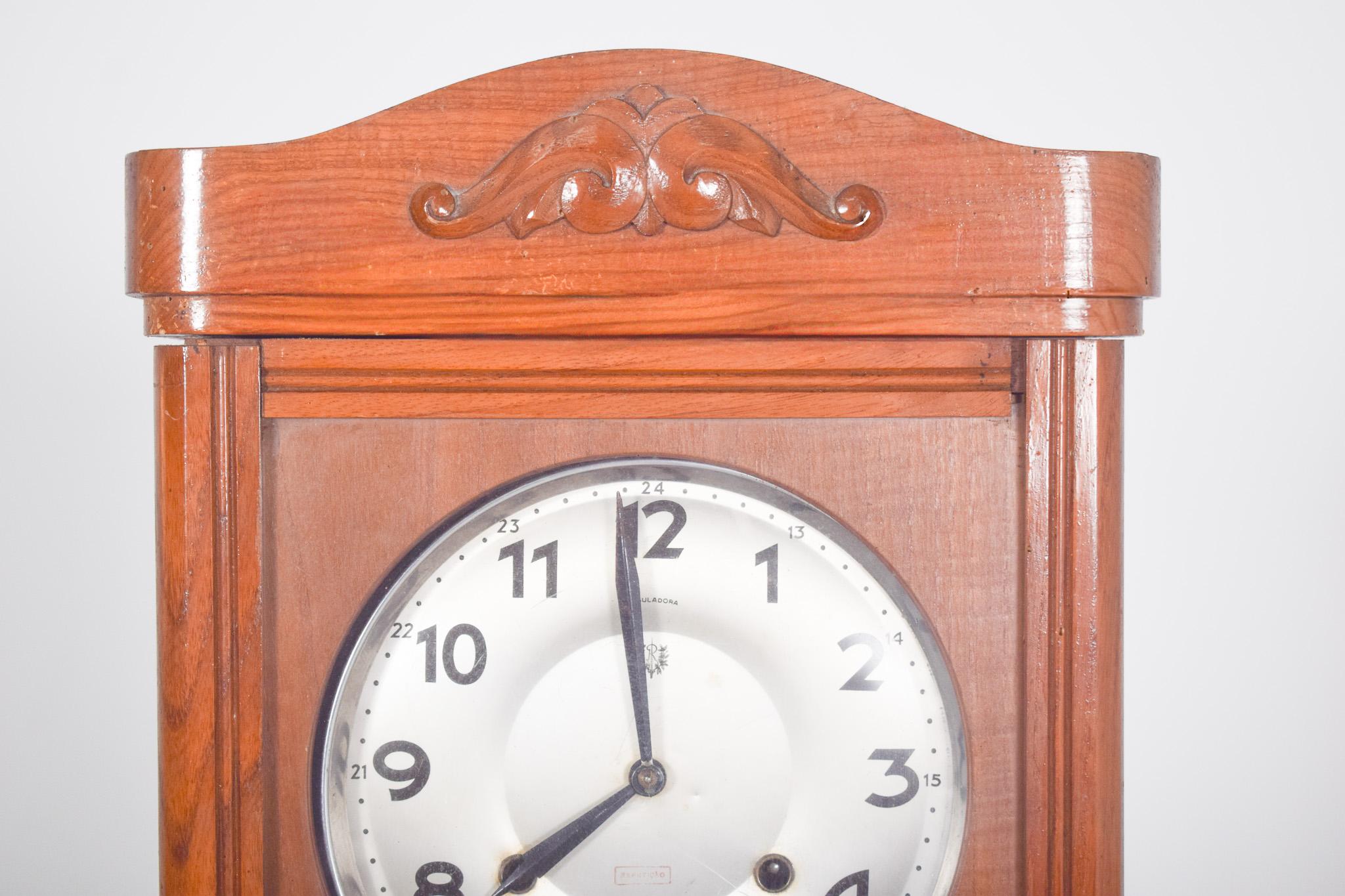 Portuguese wall clock, Fábrica Reguladora, SARL. This watch from the National Watch Factory, Reguladora SARL, Vila Nova de Famalicão, has a wooden structure and a gold dial. It has a classic design, with a rectangular shape and curved top, decorated