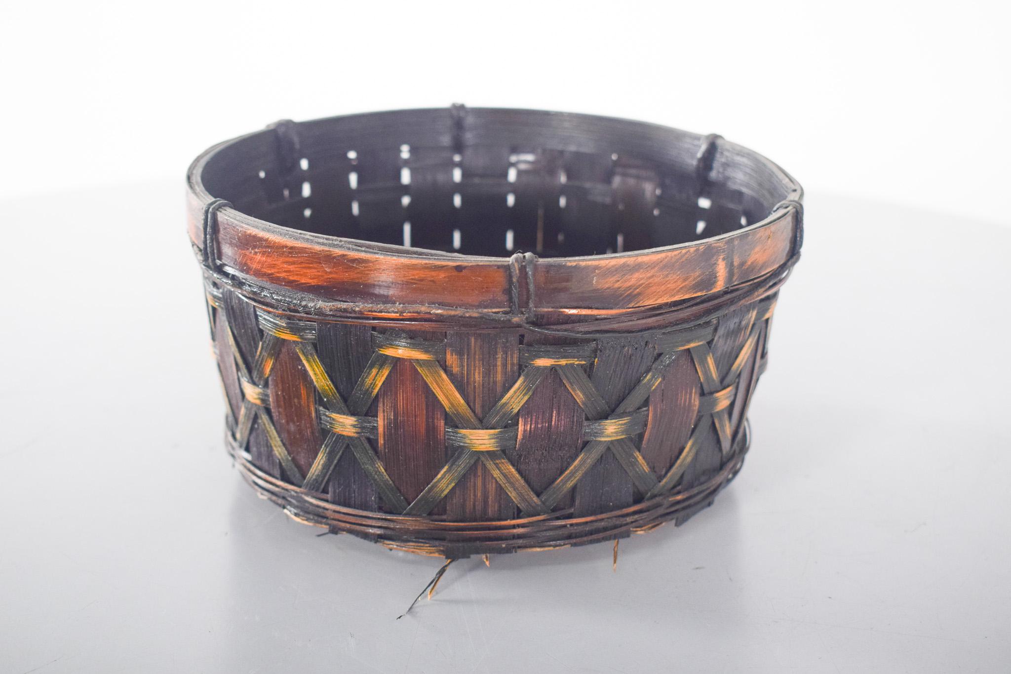Wicker basket. Worked in dark wicker with a varnished finish, revealing a warm tone between brown and black. The structure has a decorative interlacing in the shape of lozenges, obtained by carefully overlapping the plant elements. The upper edge is