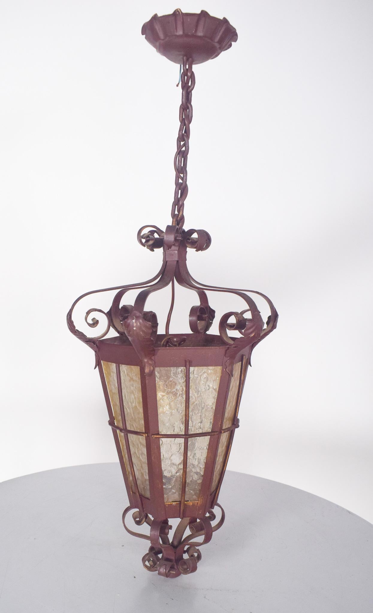 Lampadaire en fer forgé et en laiton. De style rustique, il est décoré de courbes, de feuilles et de spirales. Le cadre accueille des panneaux de verre martelé qui adoucissent la lumière émise, créant un effet diffus et douillet.
La lampe est