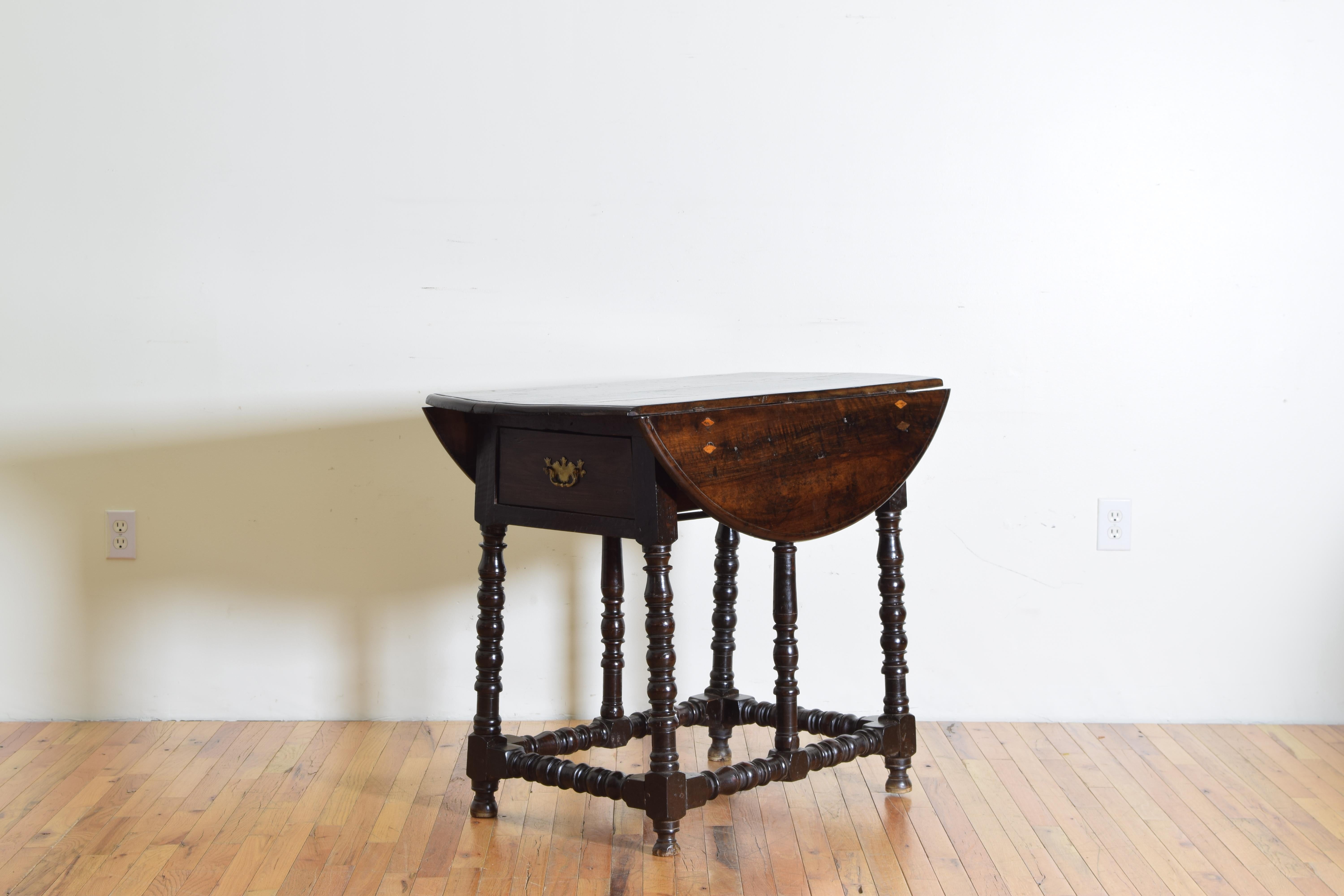 When folded down the rectangular top with rounded and molded edges rests atop a frame housing one long drawer that is accessed by both sides of the table, when the sides are upright the top forms a near circle, all of the top surfaces having inlaid